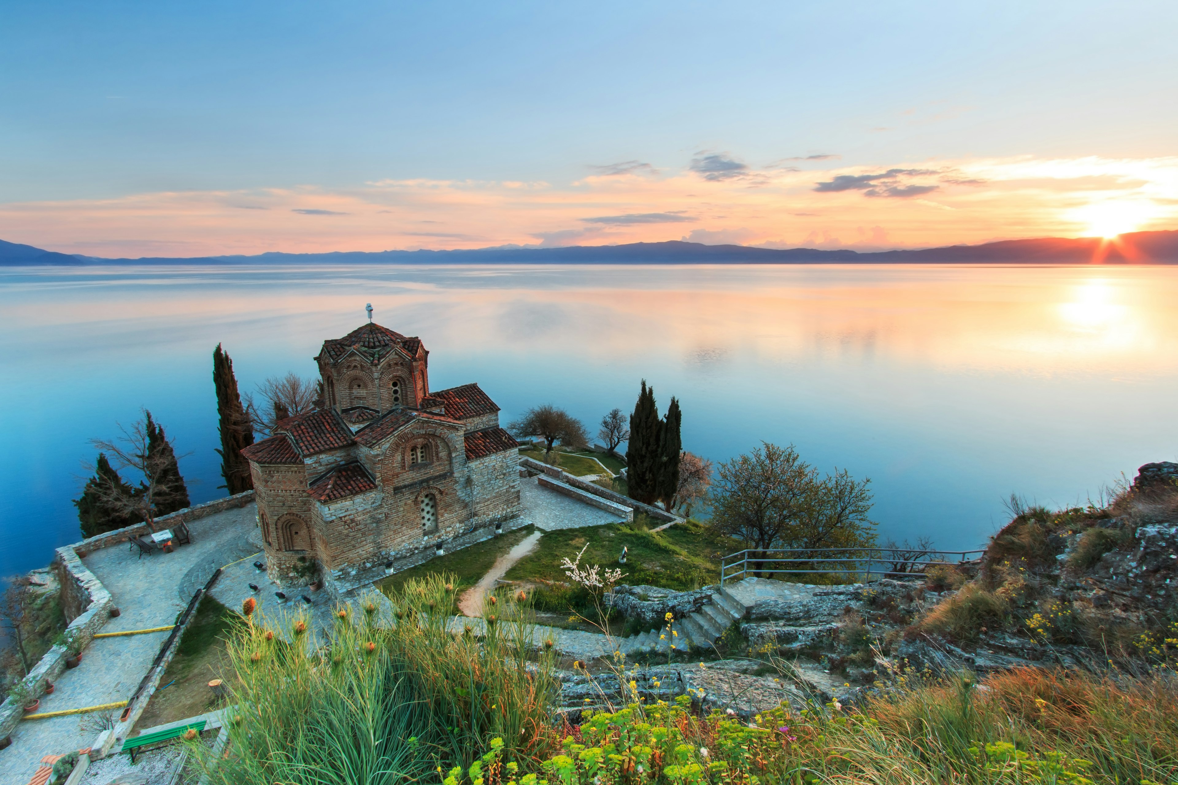 A small stone church on the edge of a lake at sunset