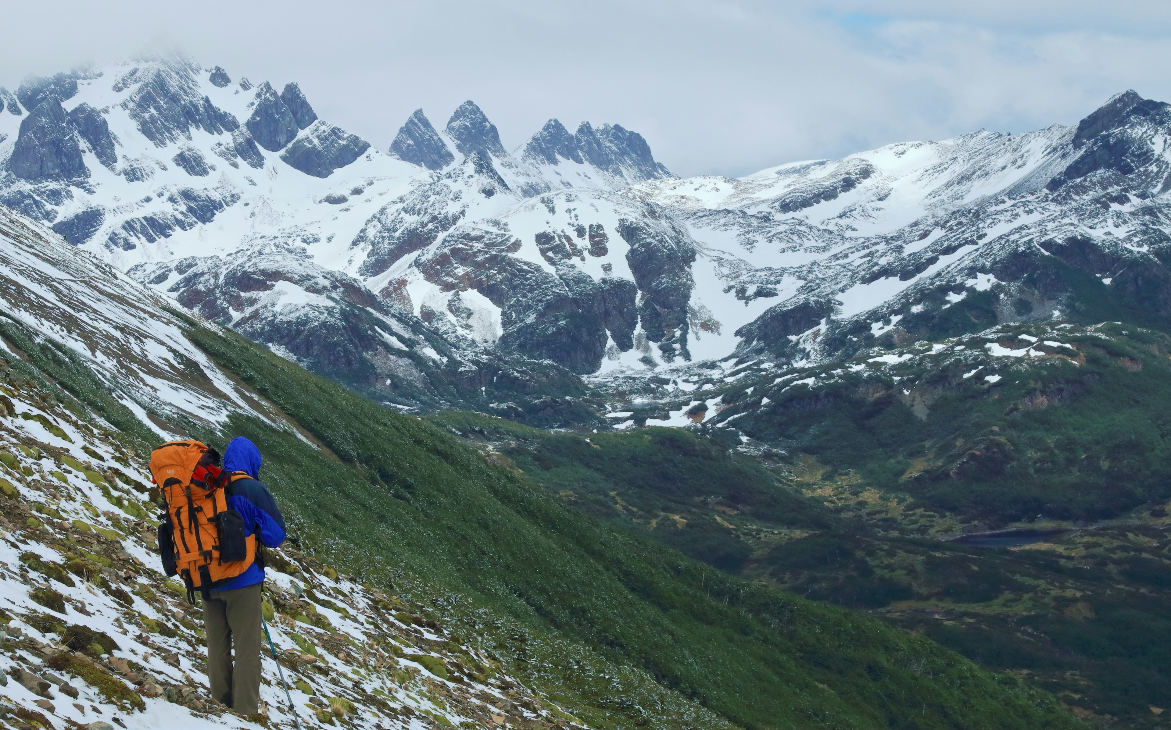 A lone hiker on the remote Dientes Circuit, surrounded by mountain peaks covered in snow in Chile