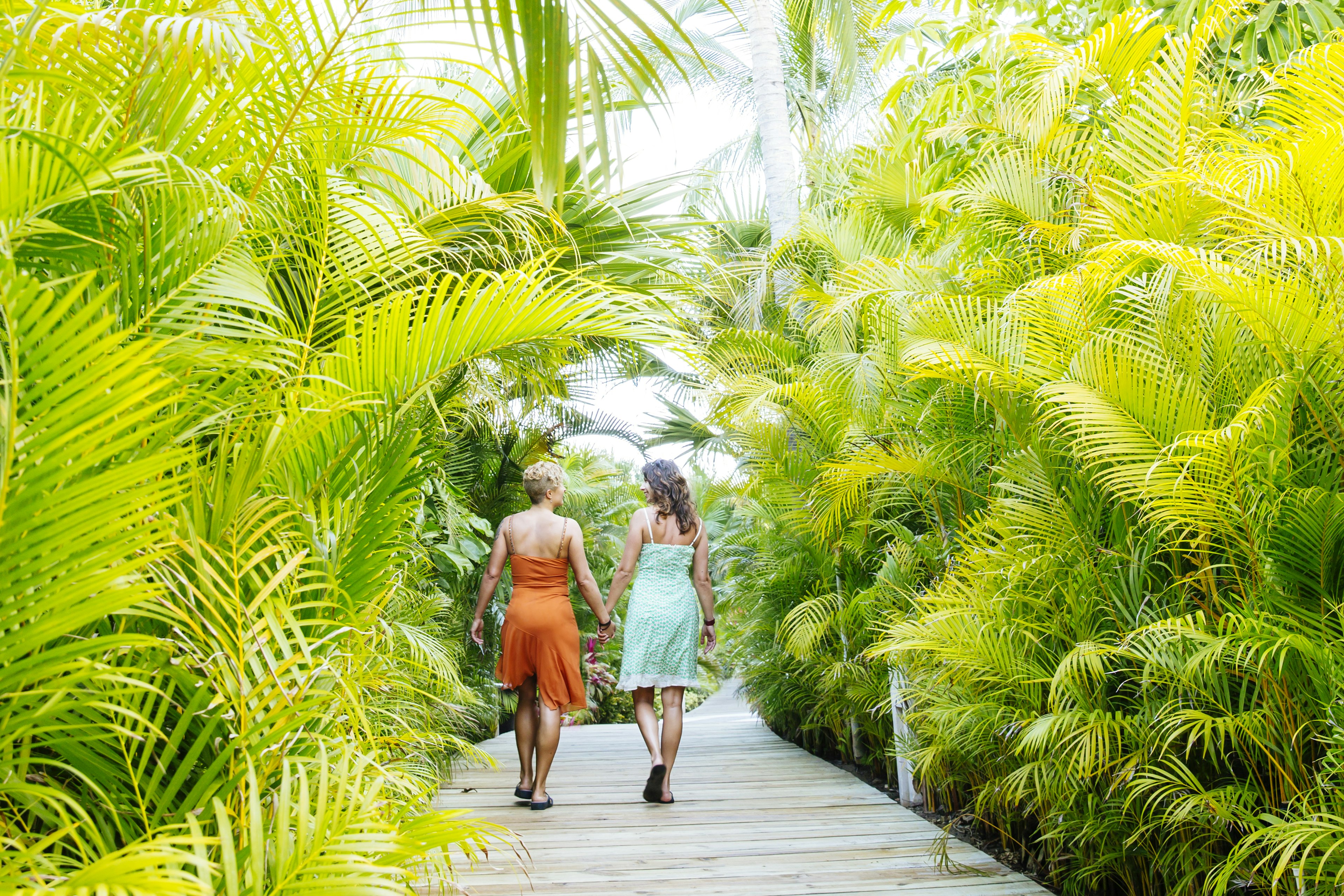 Lesbian couple holding hands on tropical walkway