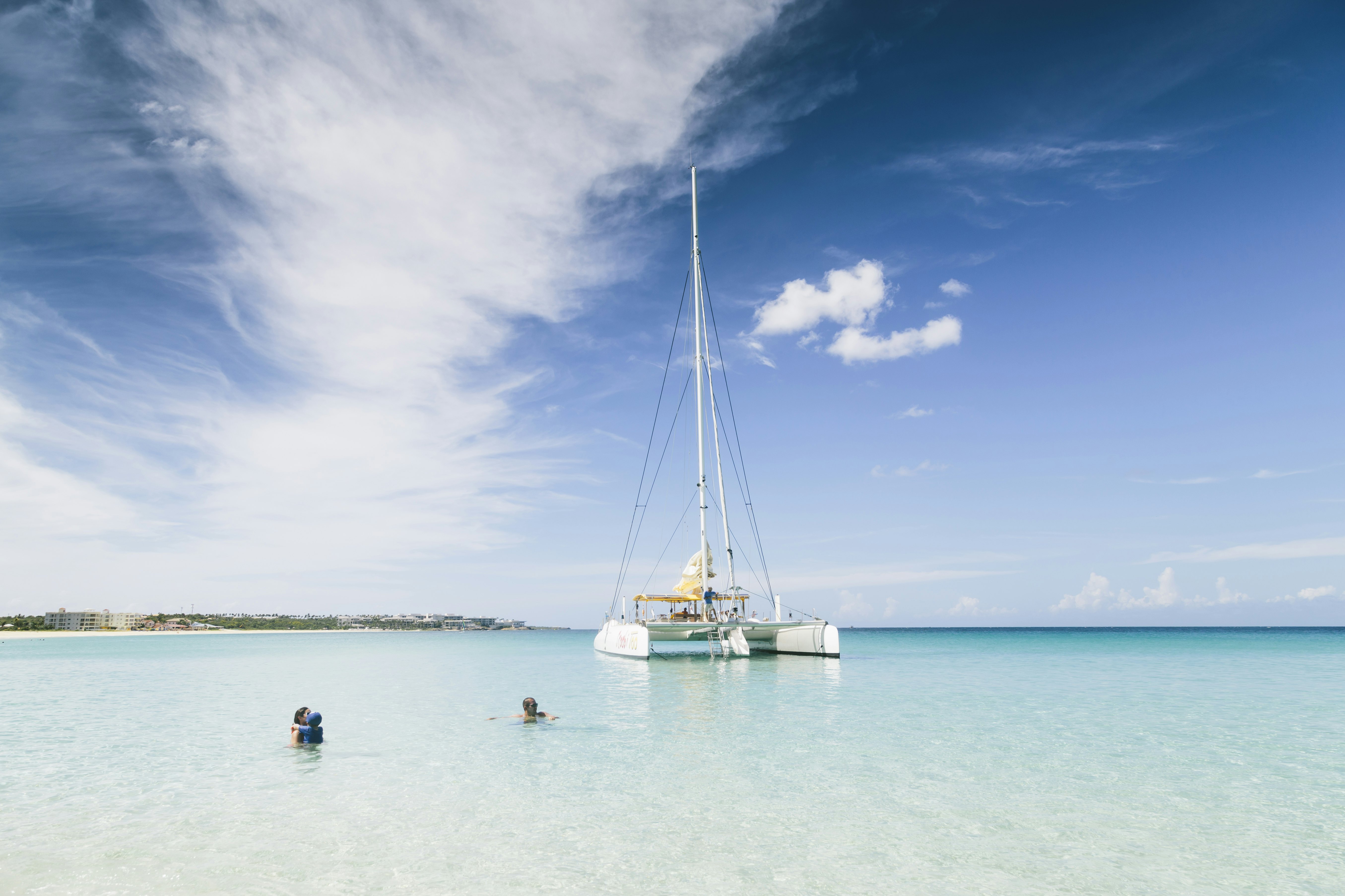 Blue sea water and white sailboat in the background, view from the blue waters of the Caribbean