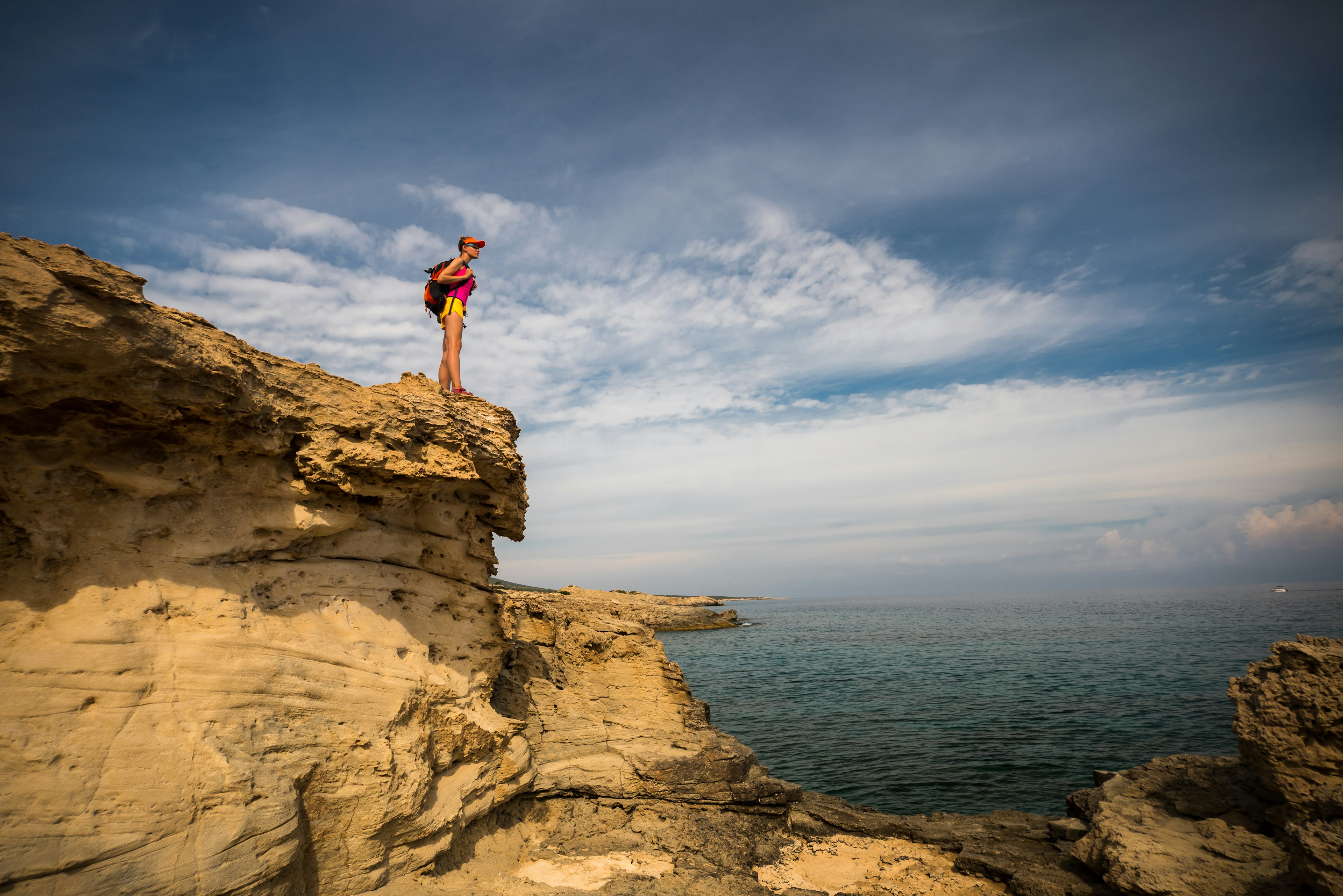 A women hiker on a rocky shoreline in the Akamas Peninsula, Cyprus