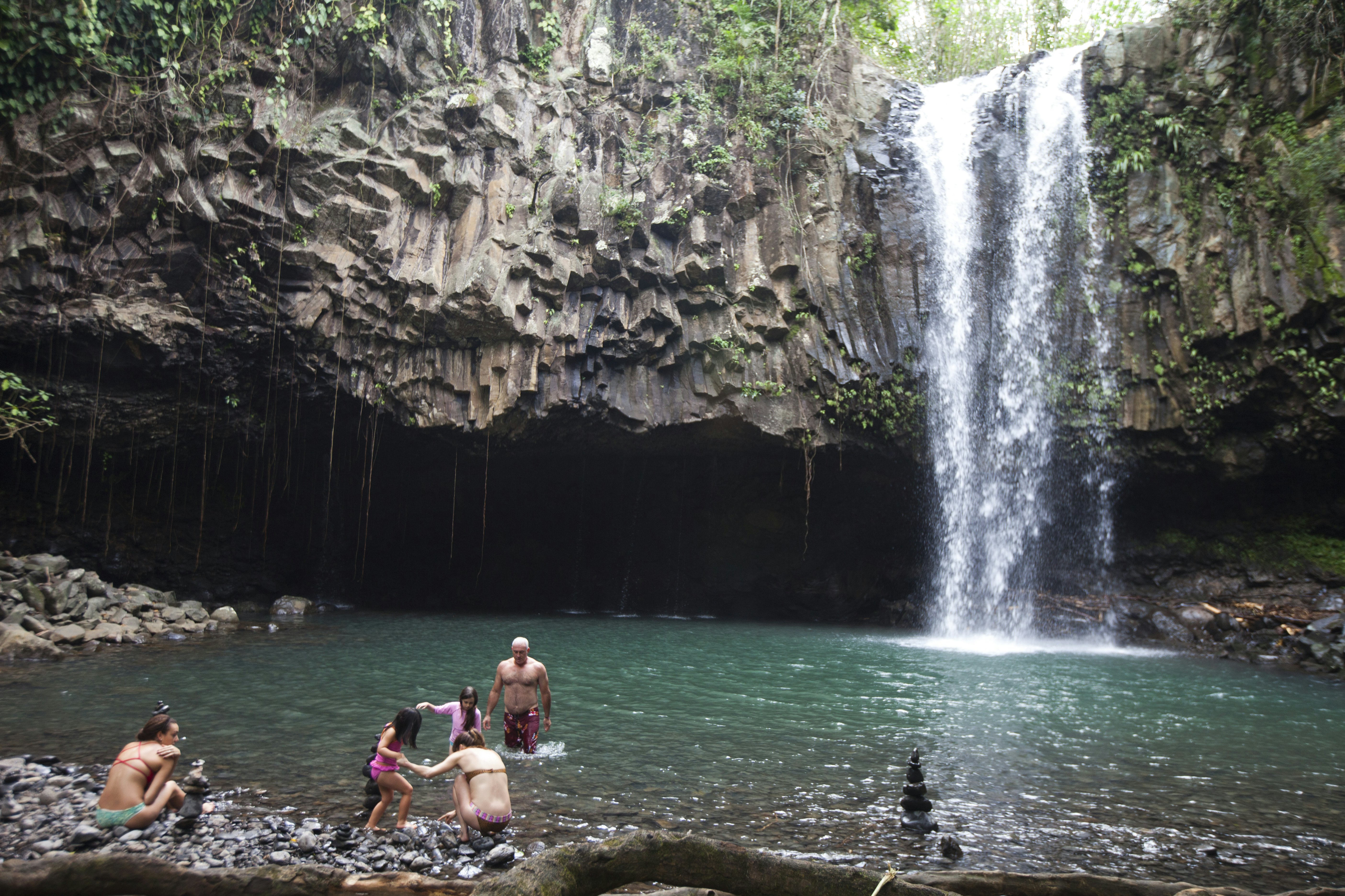 People swimming by waterfall