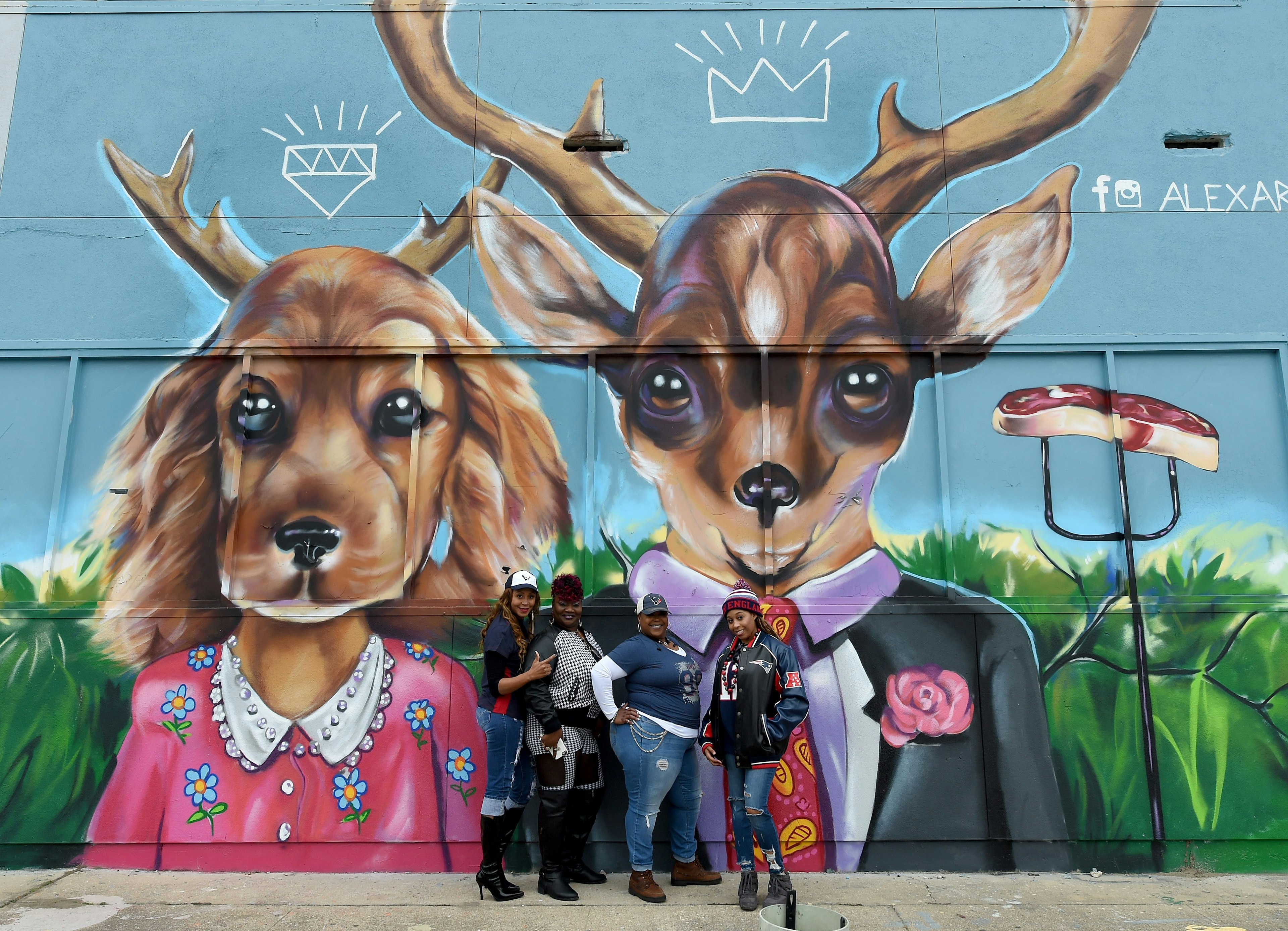 Football fans take photos in front of a graffiti-covered building in the Old Chinatown section of downtown near the  NFL Experience at the George R. Brown Convention Center on February 4, 2017 in Houston, Texas, one day before the New England Patriots play the Atlanta Falcons in Super Bowl