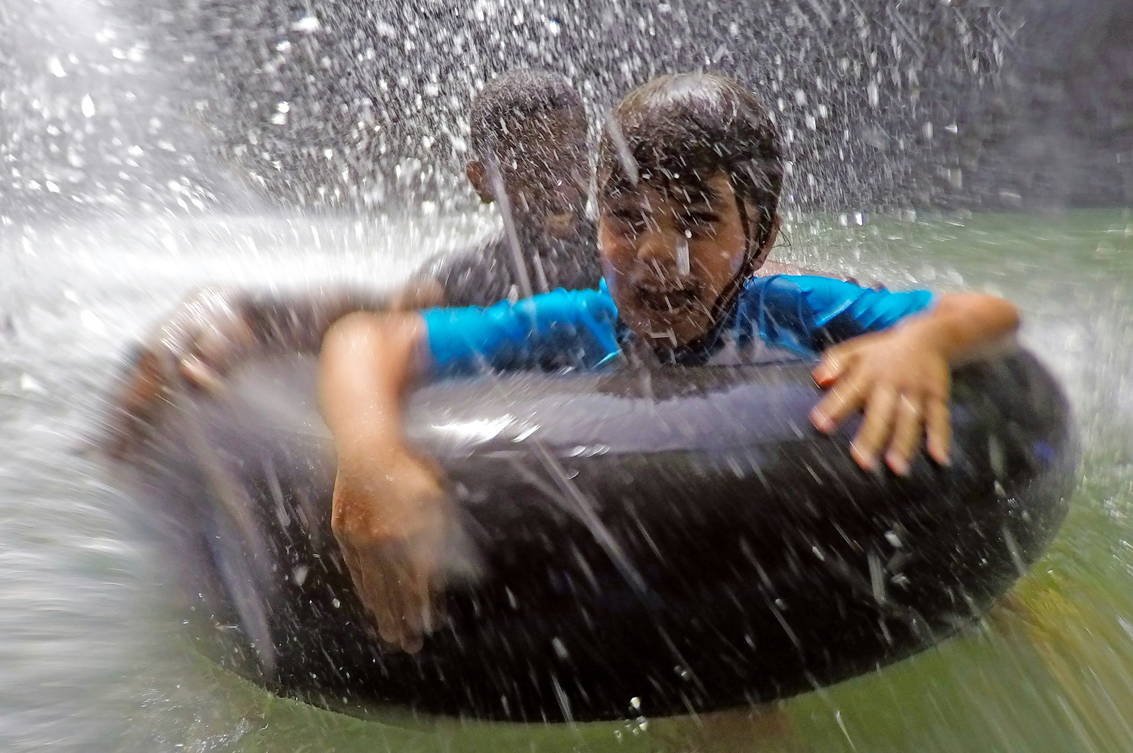 Happy children having fun under a waterfall