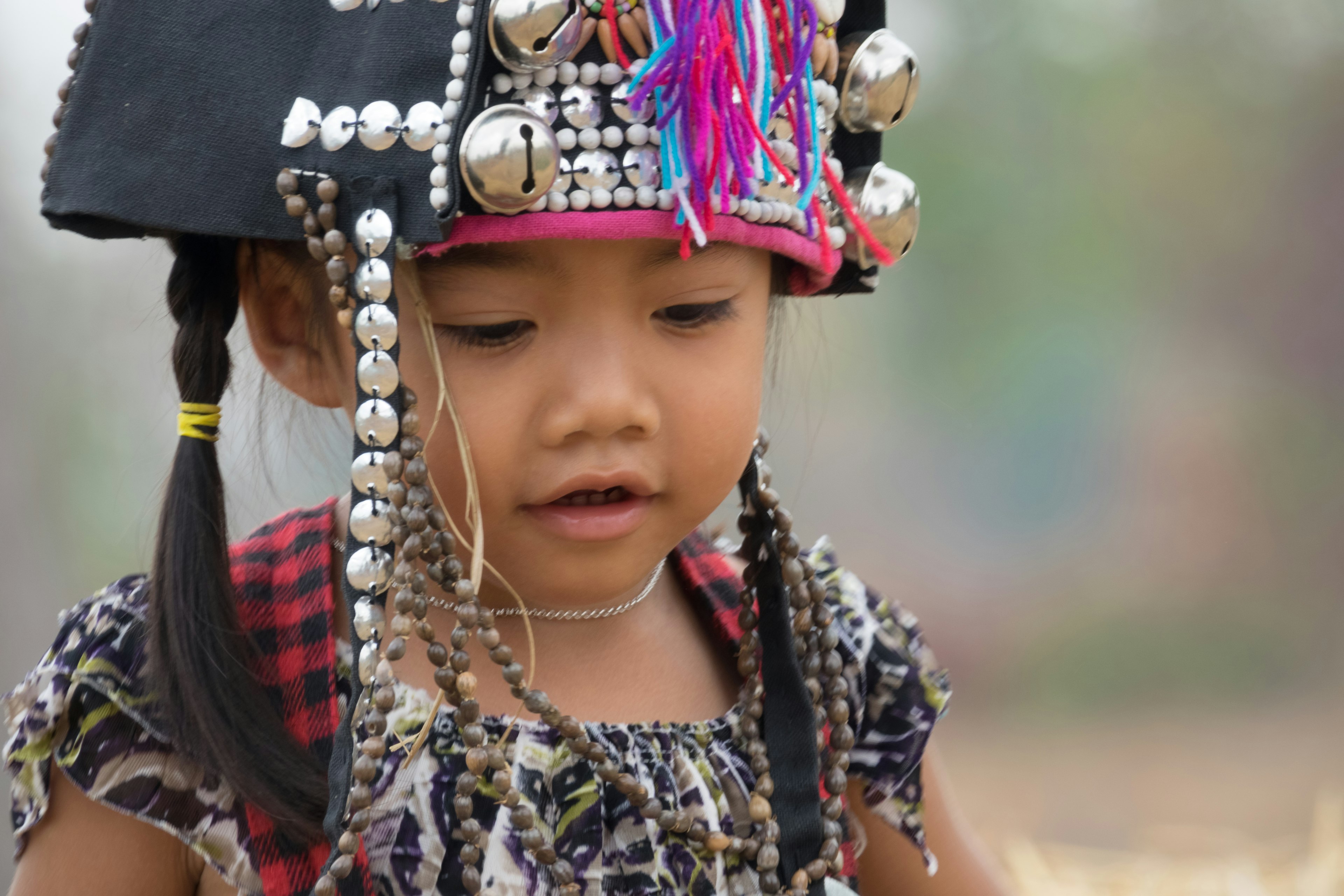 An Akha girl wears a headdress made of metal discs and brightly colored threads