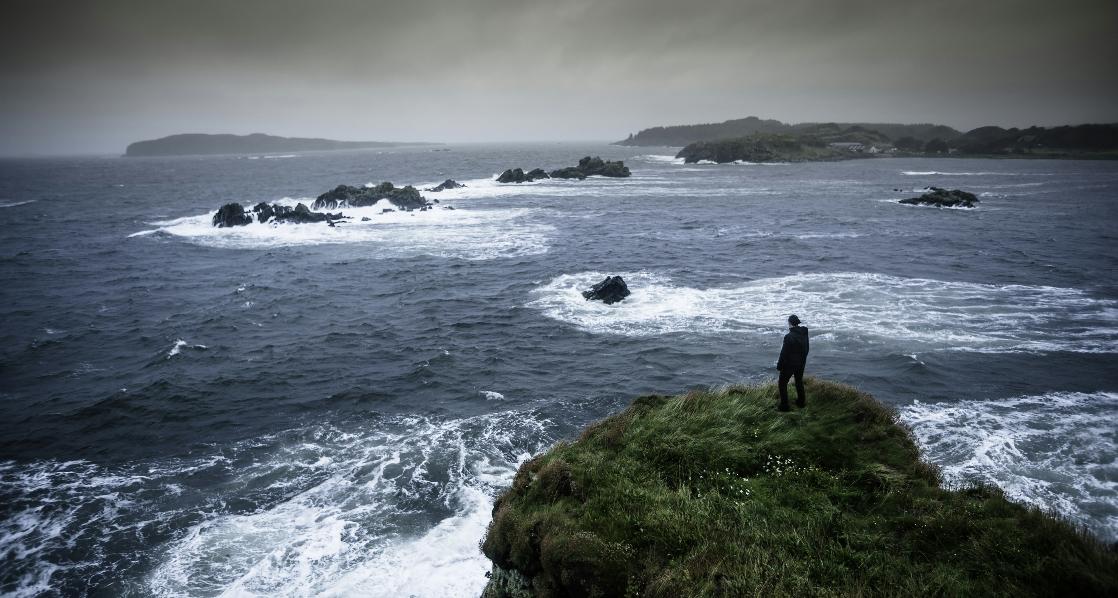 Woman standing on a cliff looking out to sea on the Isle of Islay, Scotland