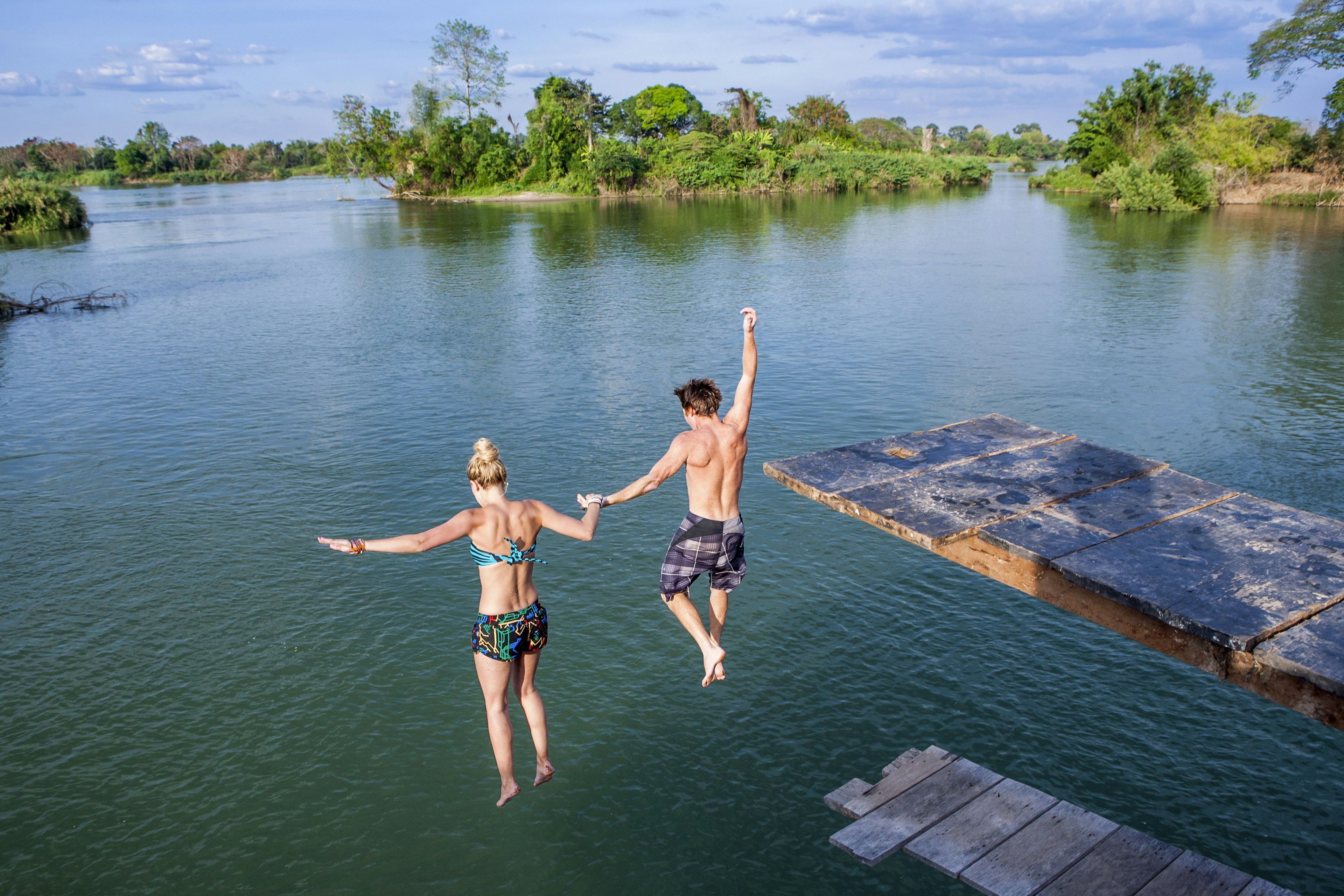 Two people jump off a platform into the Mekong River off of Don Det Island, Laos