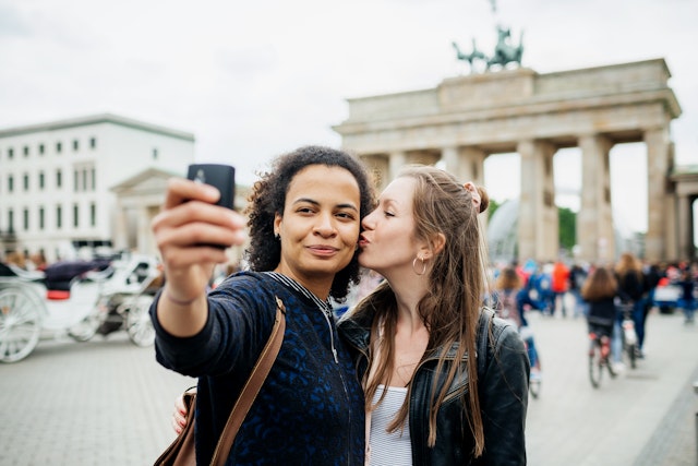 Young lesbian Couple Stop To Take A Selfie At Brandenburg Gate in Berlin