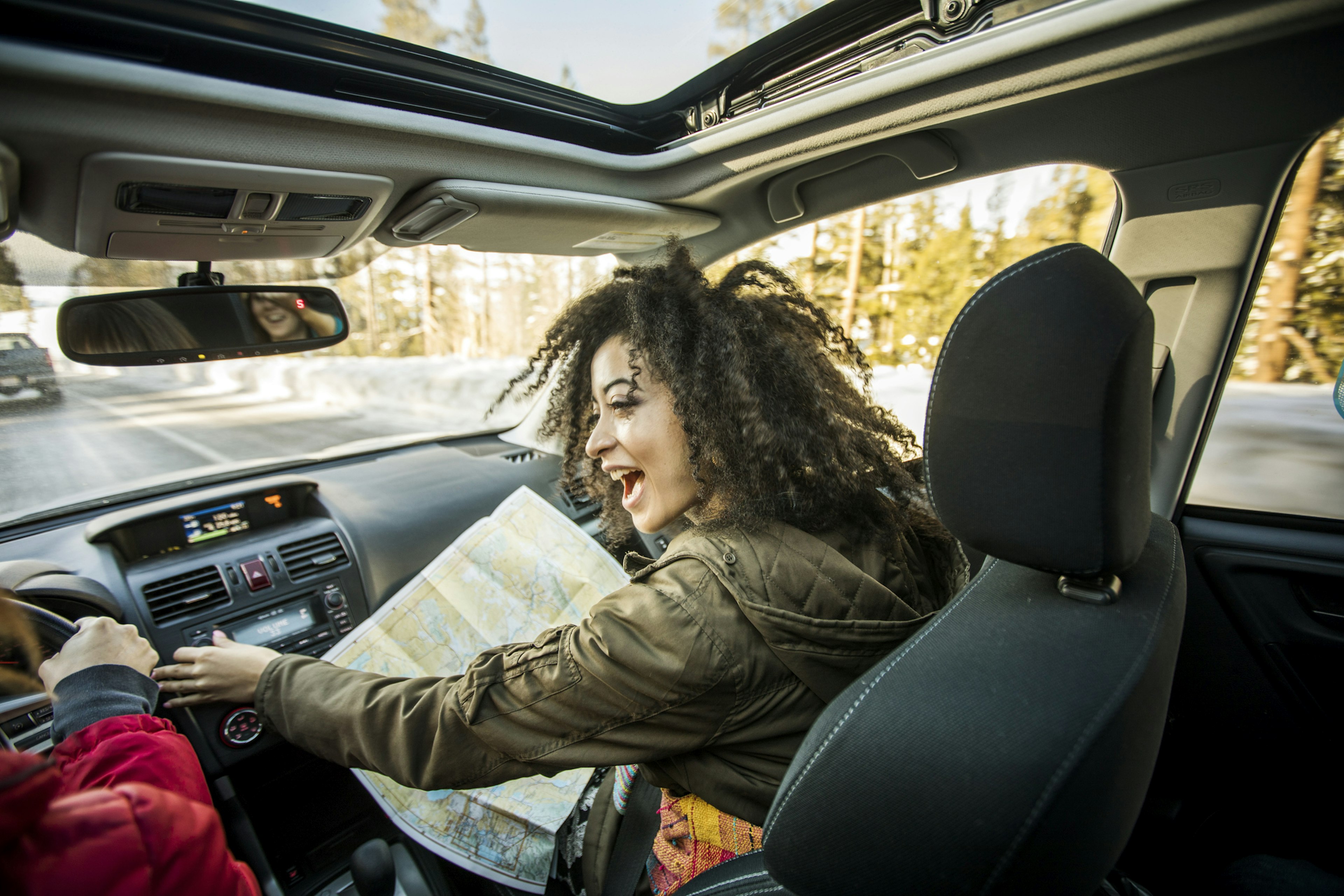 Woman driving car, friend in passenger seat looking at map