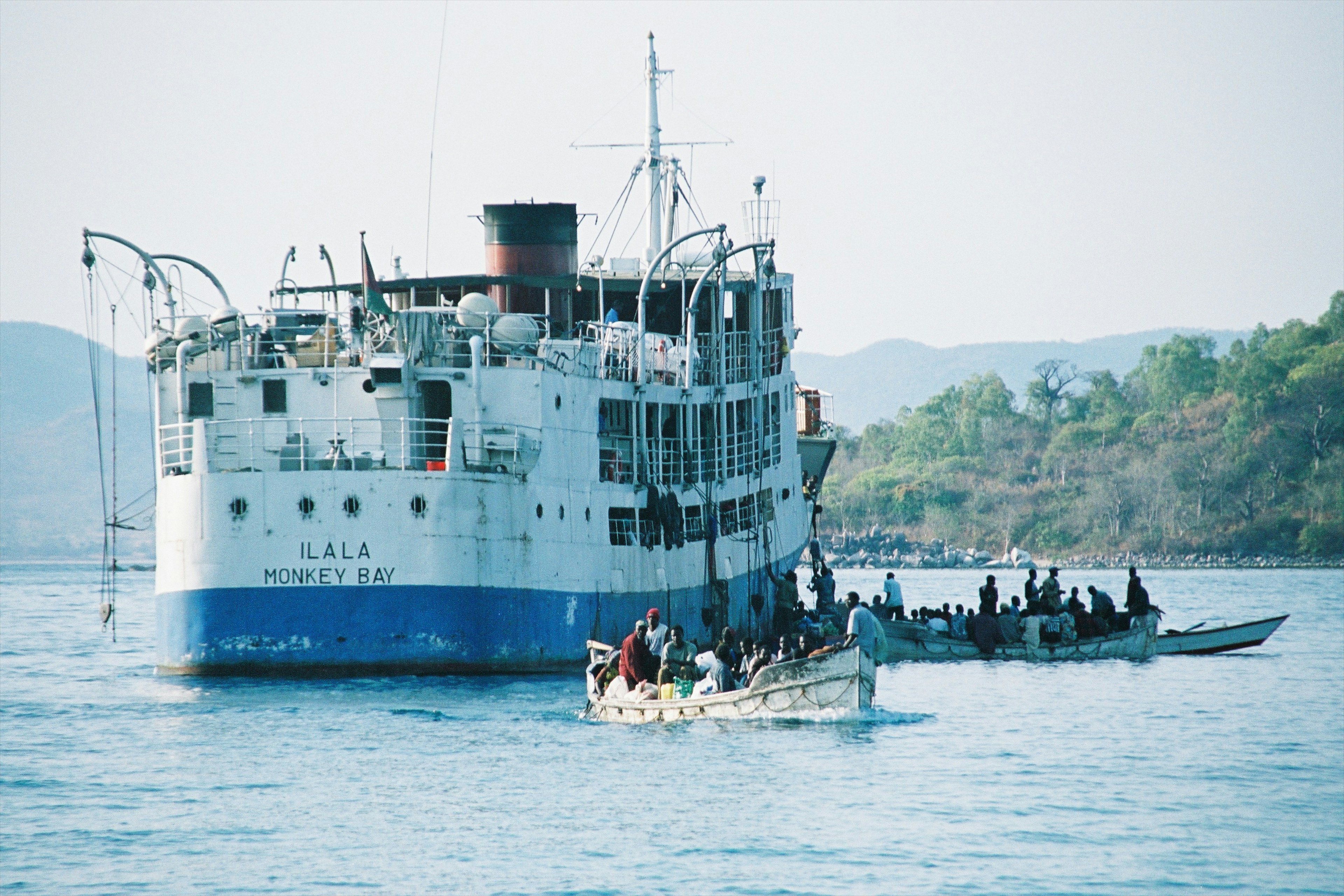 A large passenger ship stationary in a bay being loaded by smaller boats