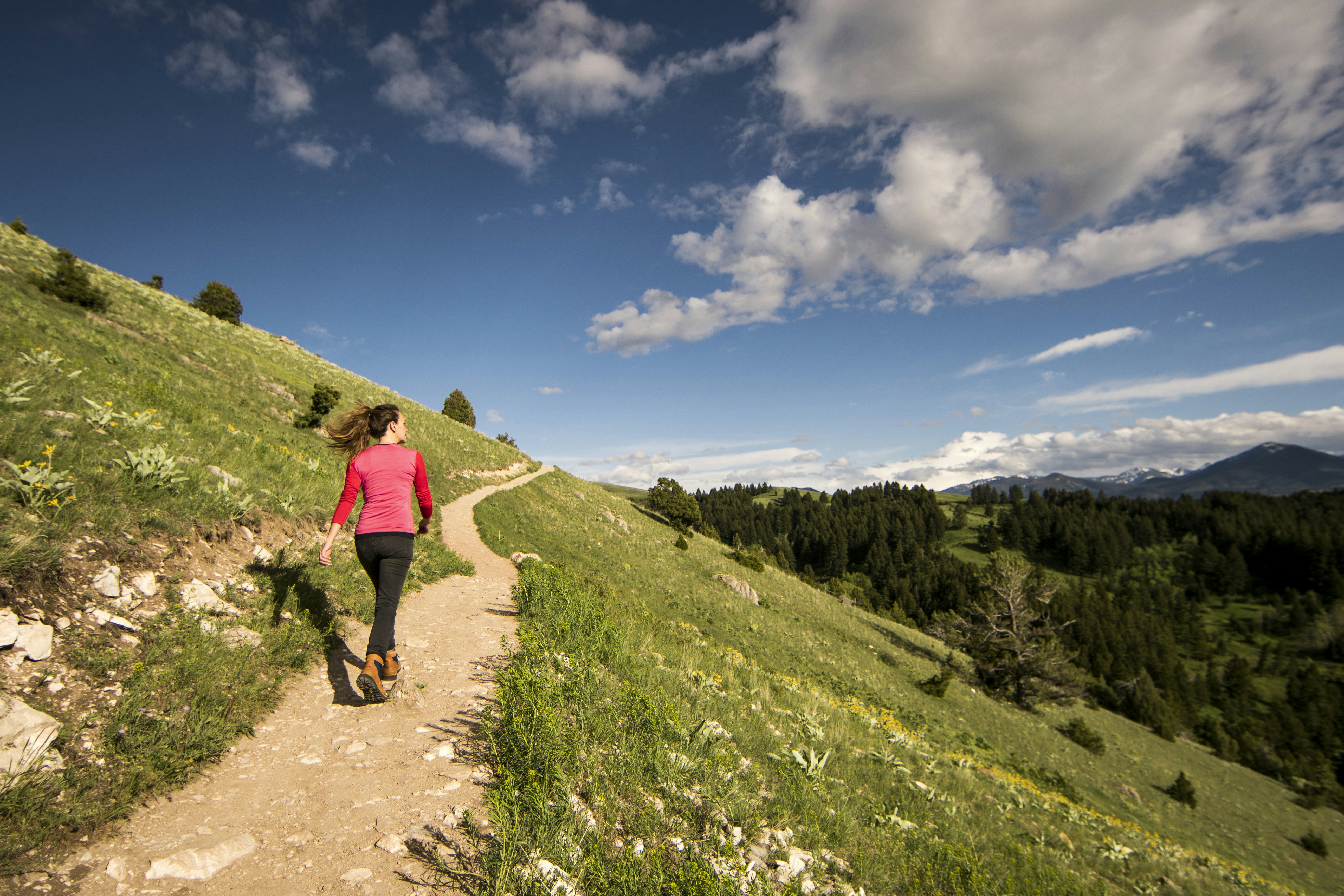 A woman walking a trail on a hillside near Bozeman, Montana