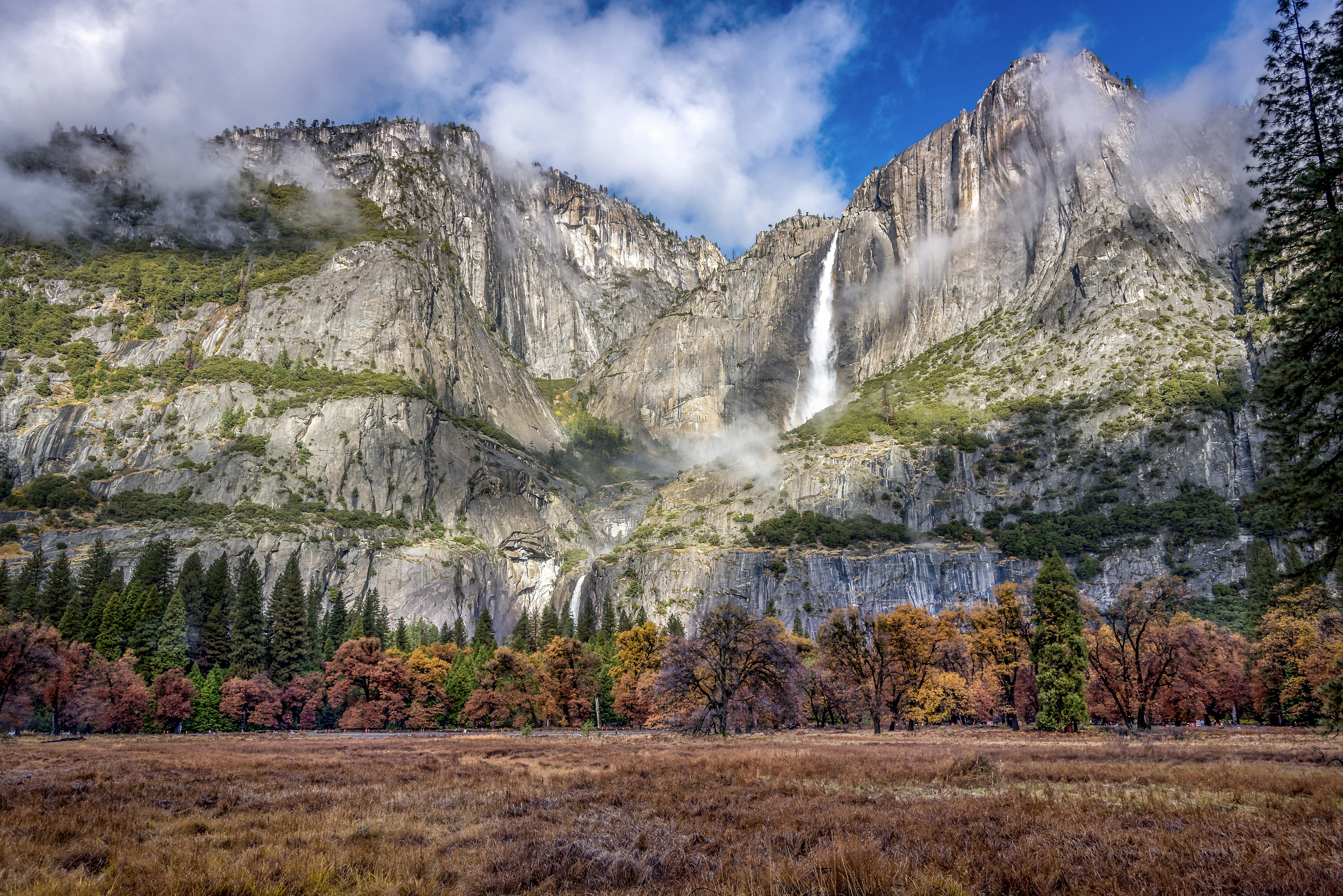 A long thin waterfall plunges down from a high-up rocky formation