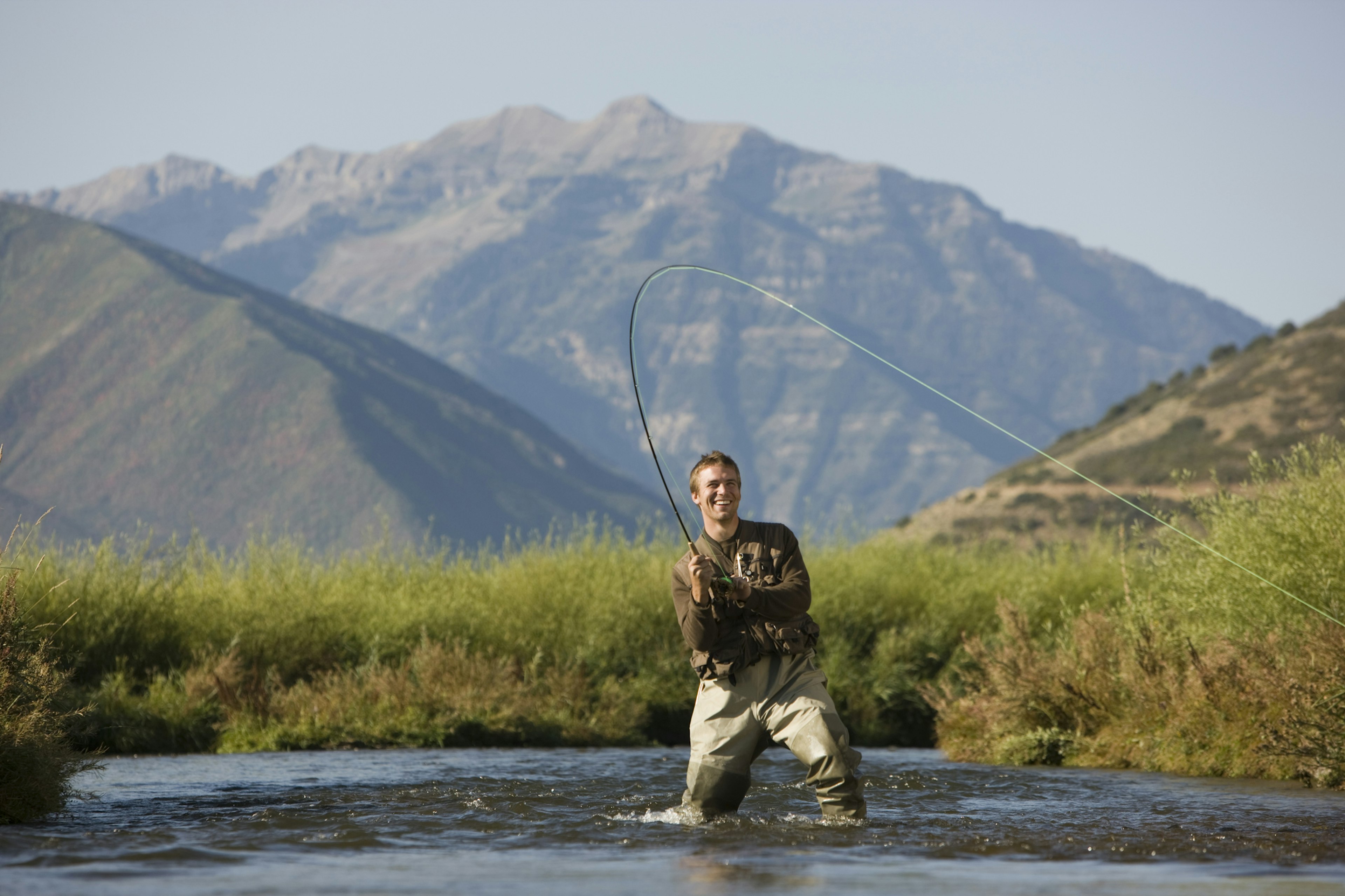 fly fisherman fishing in a mountain river