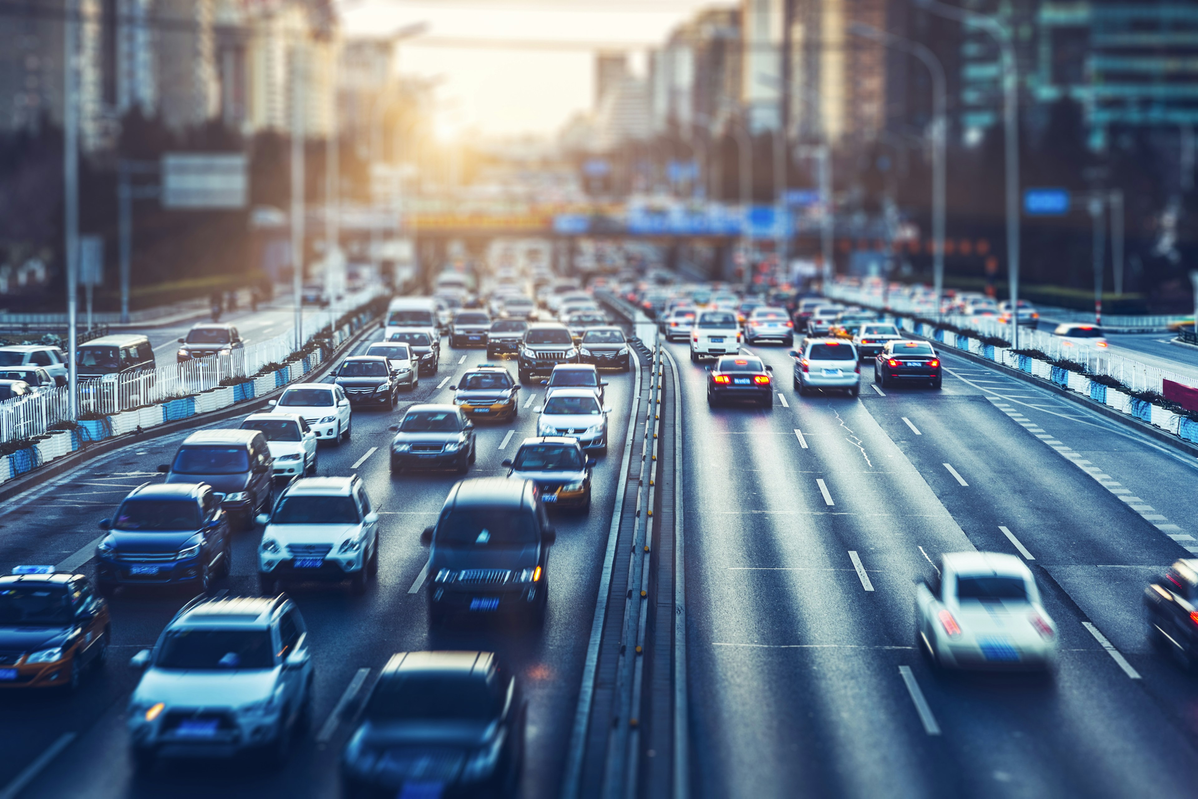 Two queues of rush-hour traffic across six lanes wait in a wet, grey downtown Beijing, China