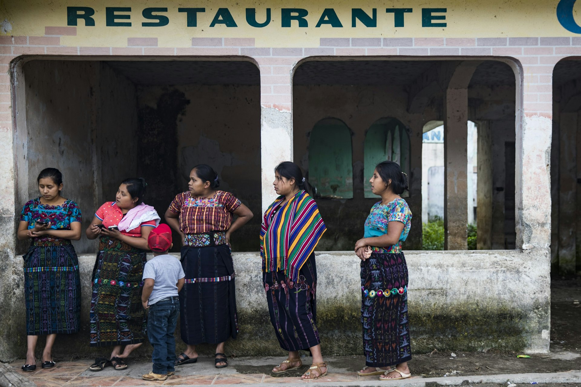 Women wearing traditional Mayan dress wait for a boat at the docks in San Pedro on Lake Atitlan, Guatemala