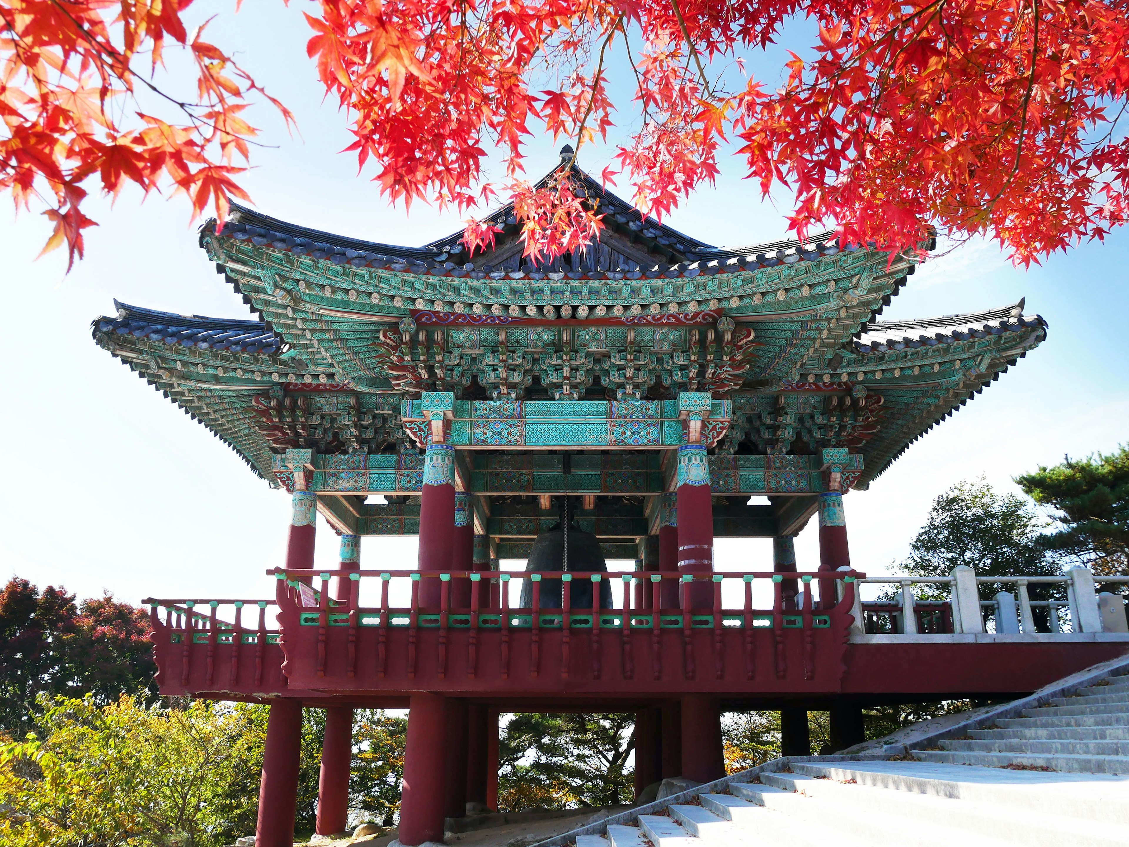 Red maple leaves in the foreground, in front of the bell pavilion at Seokguram Grotto in Gyeongju, South Korea.