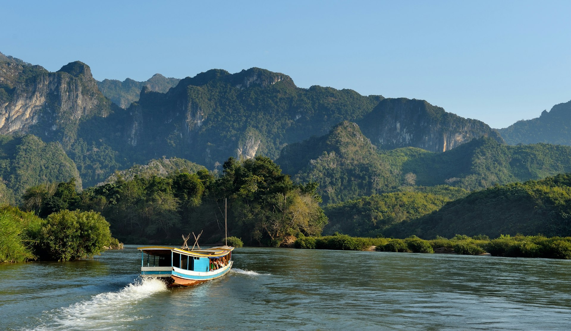 A boat on the Mekong River against a backdrop of karst outcroppings, Laos