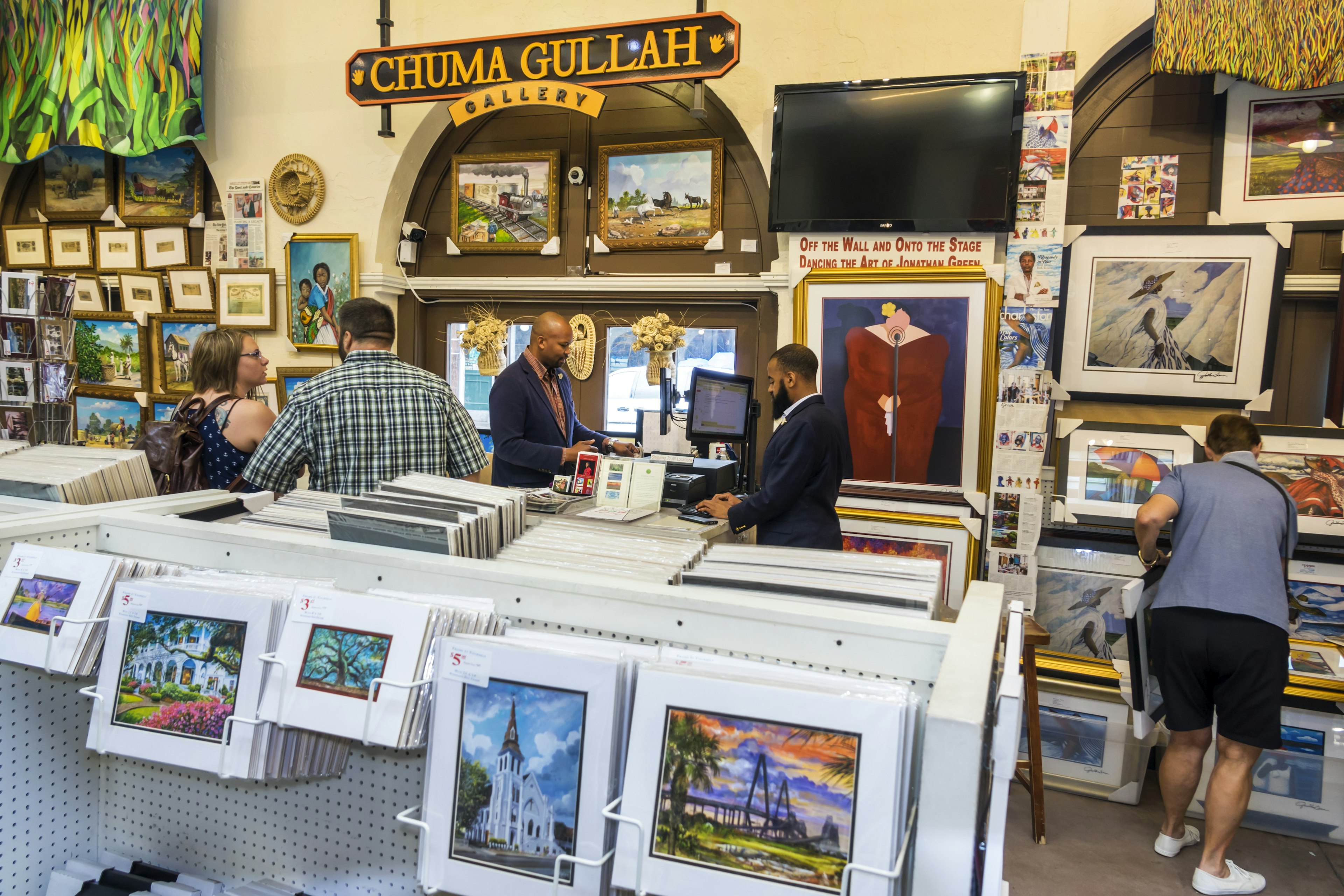 People buy prints of other colorful artwork at the Chuma Gullah Gallery in the Charleston City Market