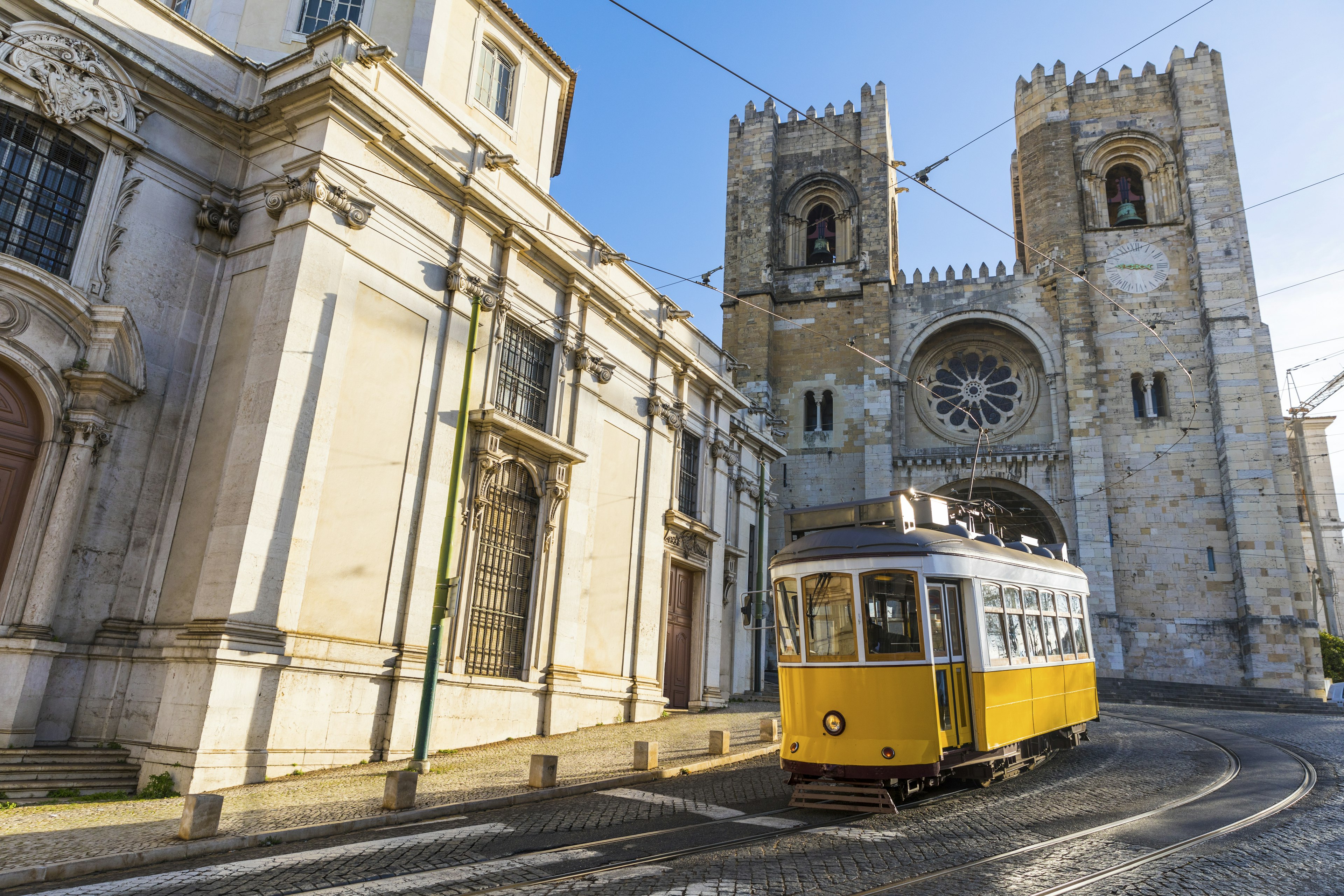 Typical yellow tram in front of Sé de Lisboa in Lisbon, Portugal