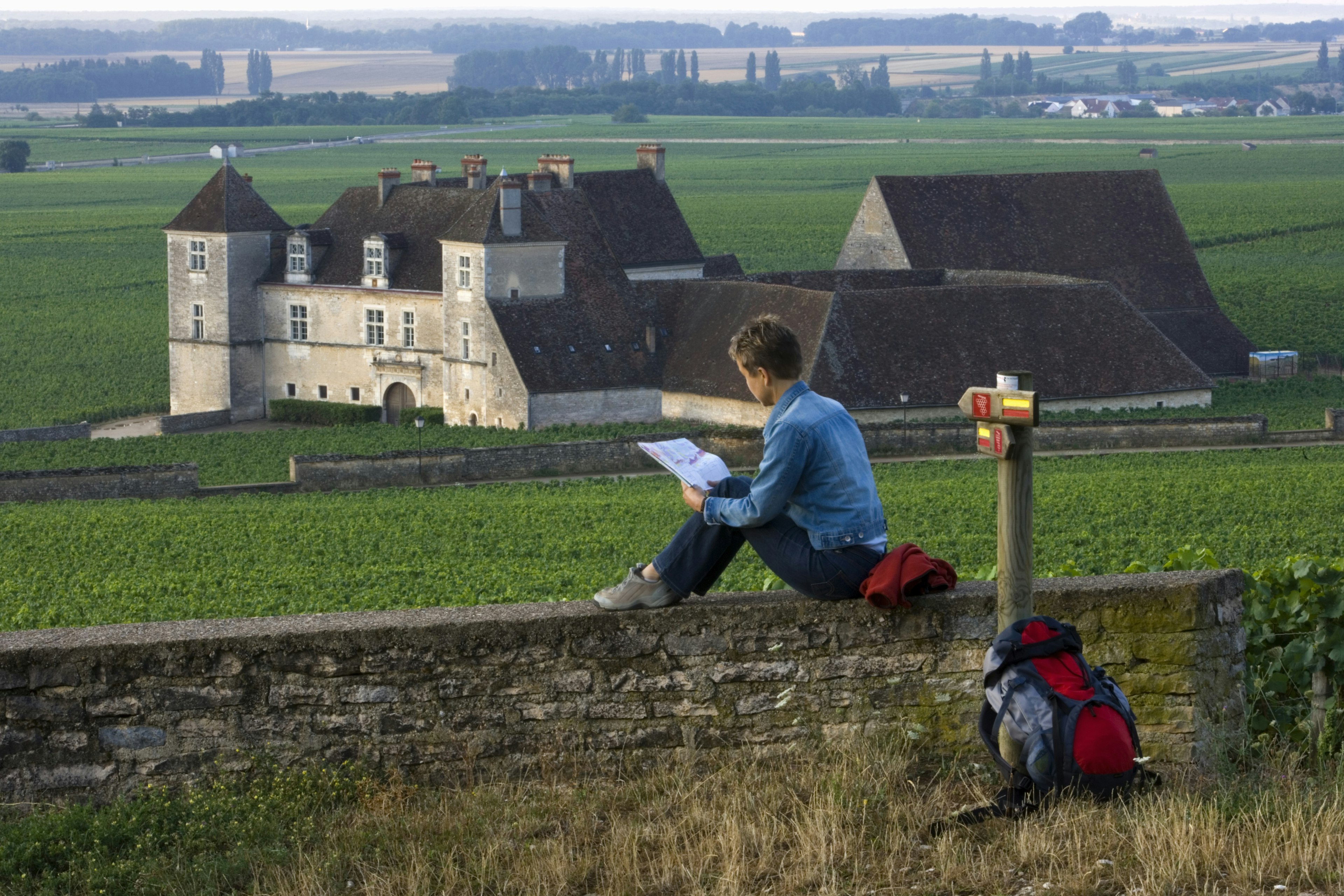 A woman hiker pauses at Castle Clos de Vougeot near Beaune