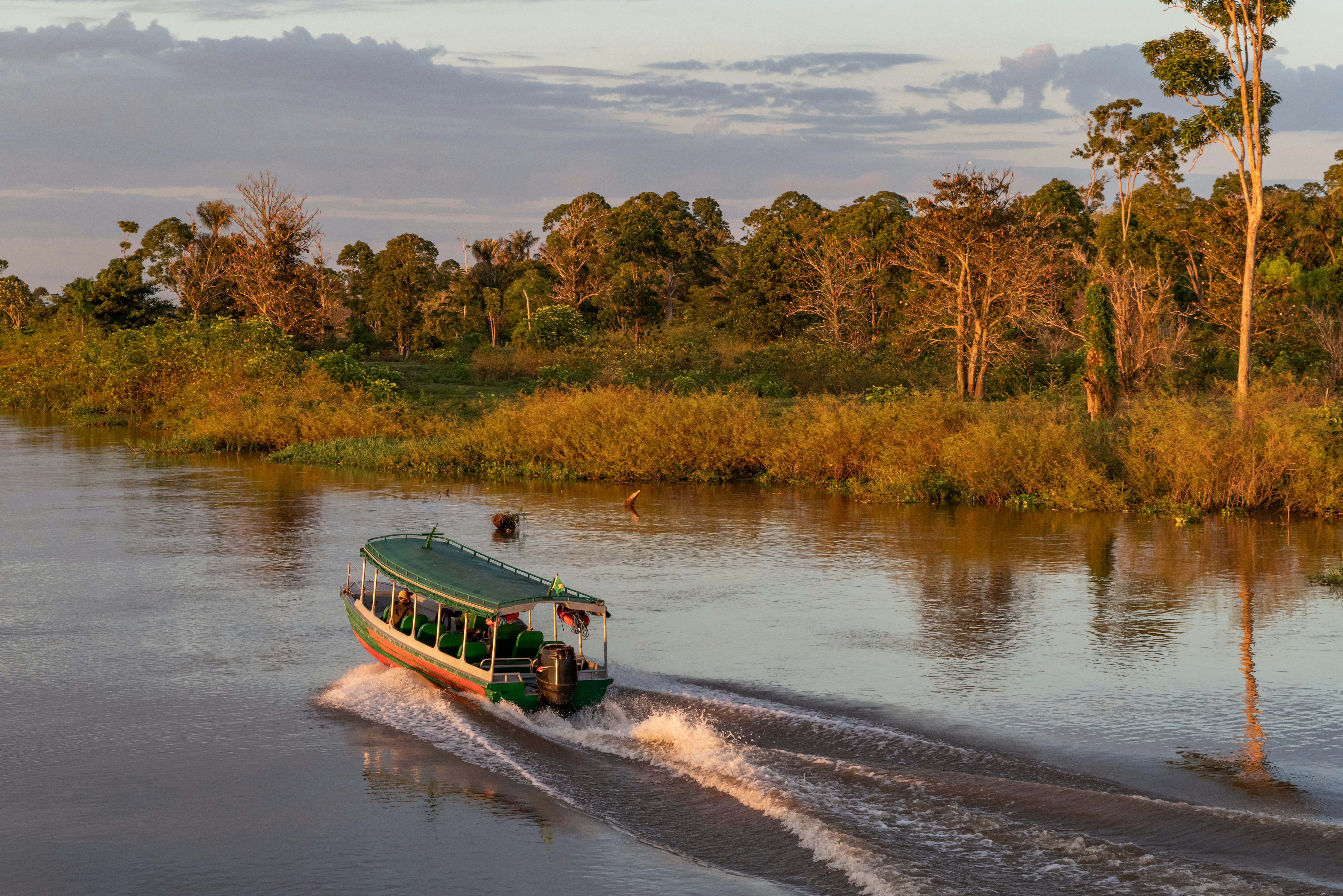 A passenger riverboat cruises down the Amazon at sunrise