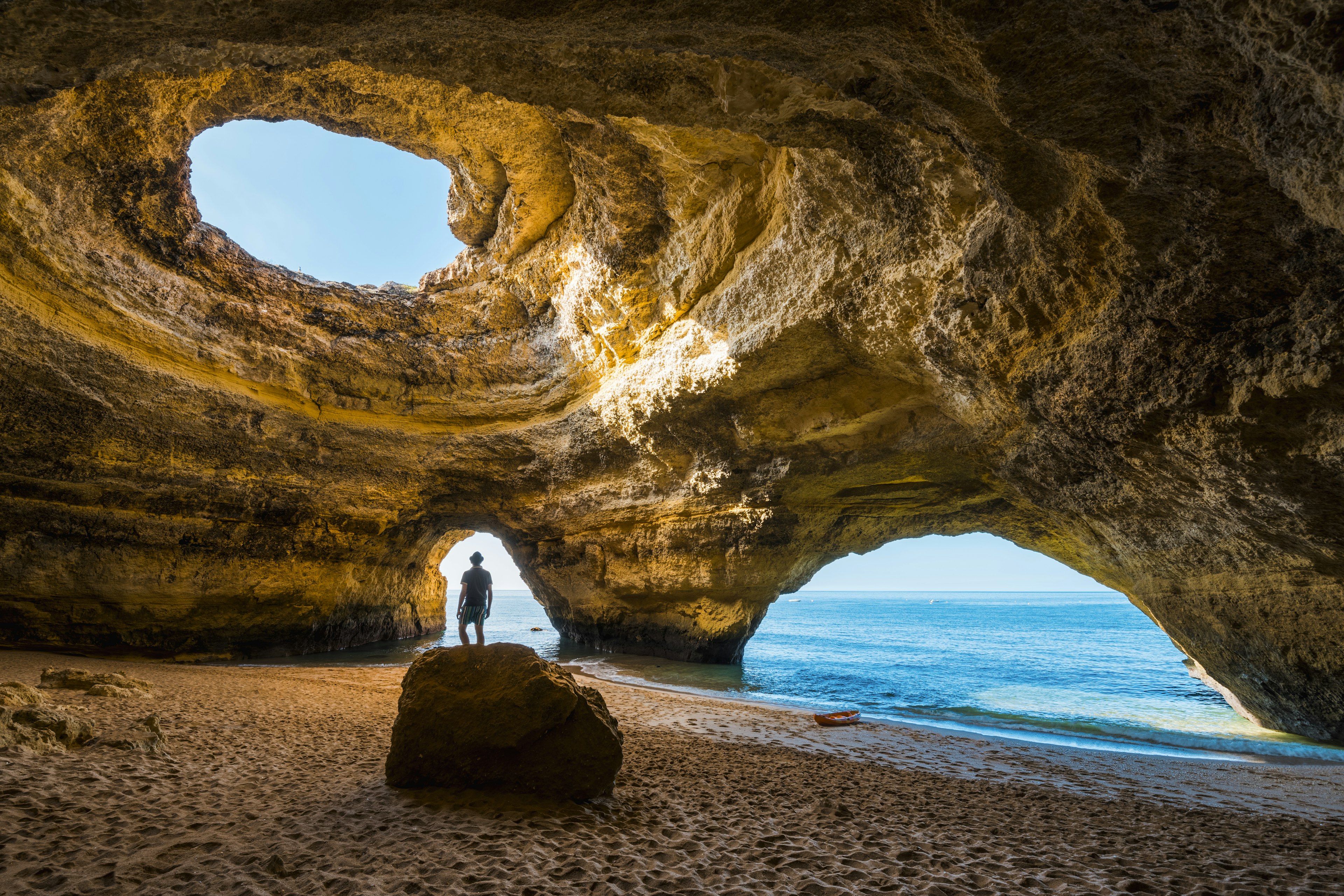 A man looks up into the opening of the inside the Benagil Caves, the Algarve, Portugal