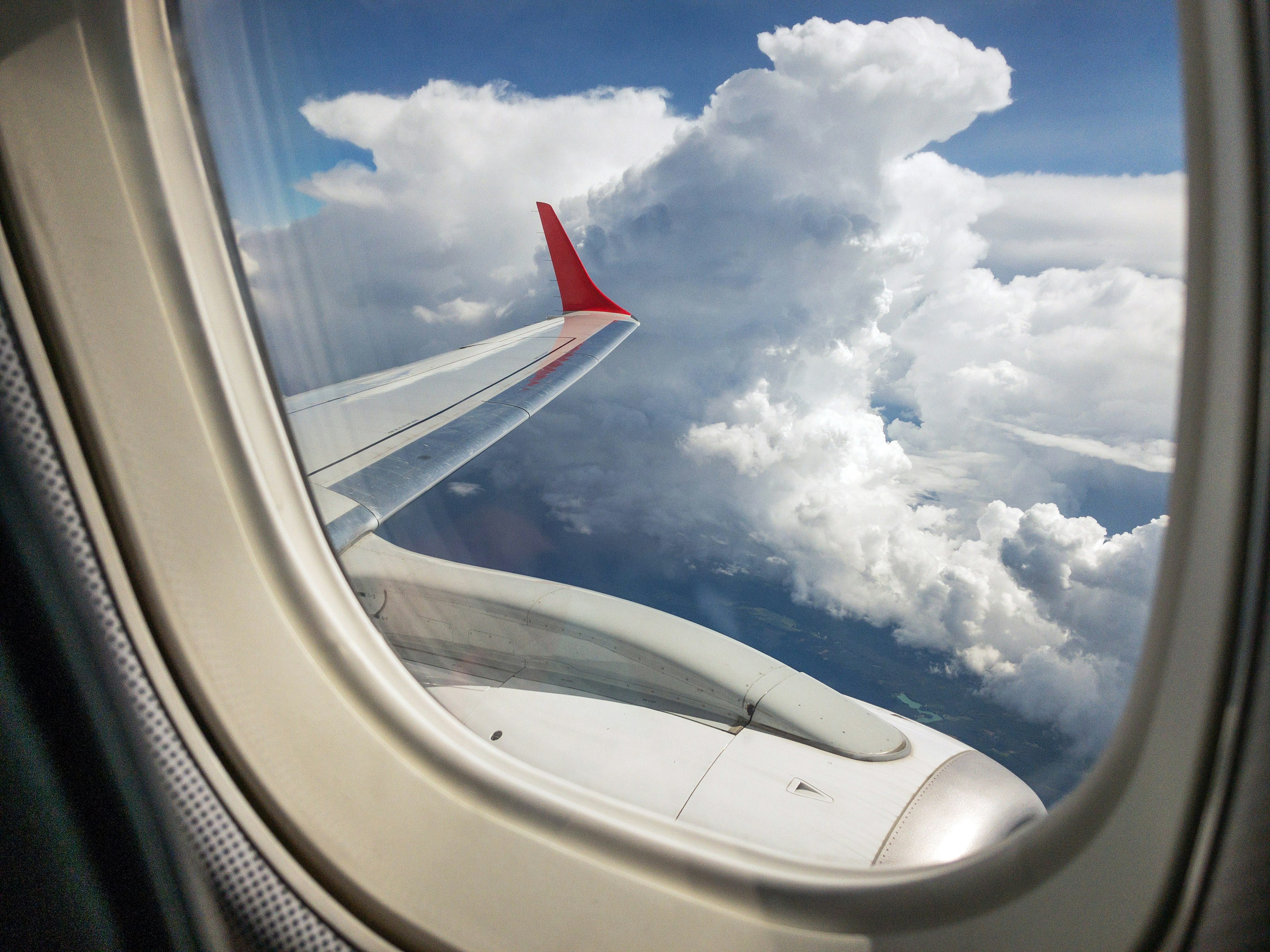 A view out over the wing of a plane in mid-flight. There are several groups of white clouds