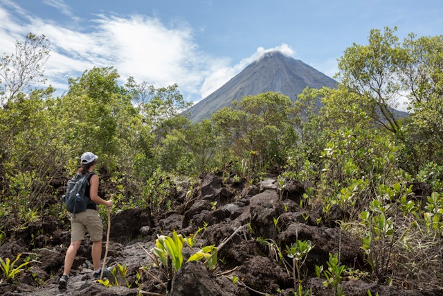 Woman hiking the Arenal 1968 Trail, Costa Rica, in front of the Arenal volcano