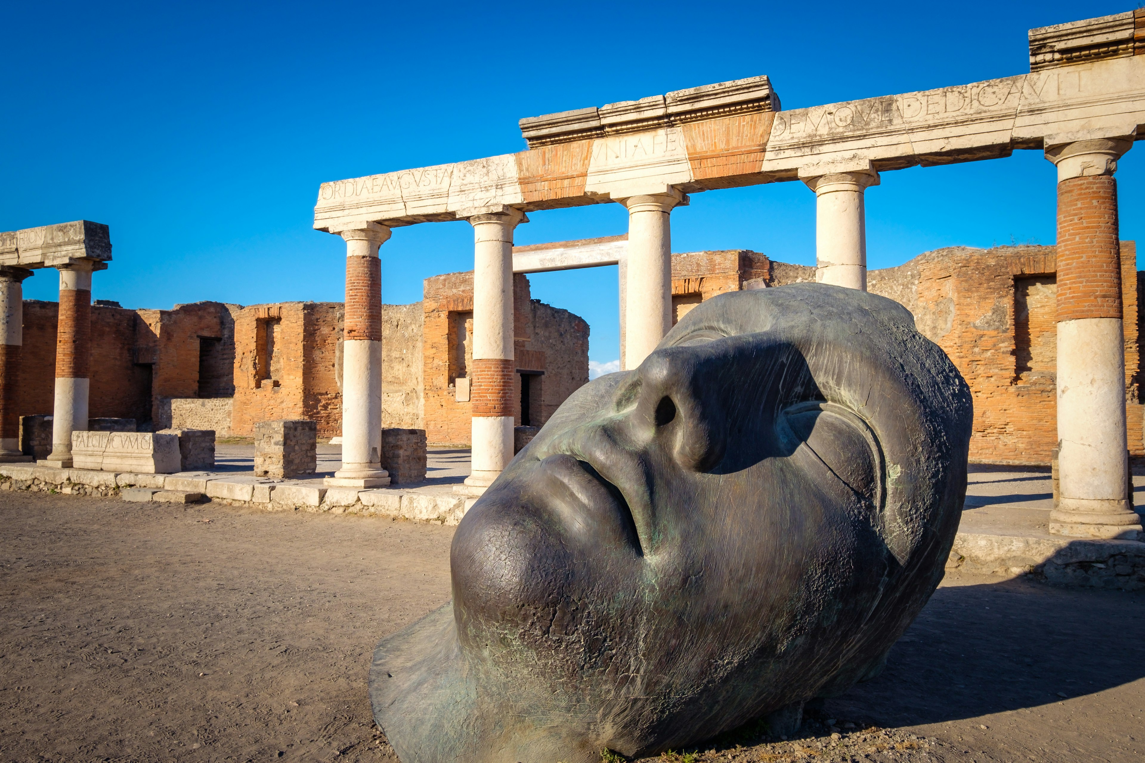 Scenic view of ruins and bronze statue in ancient Pompeii city