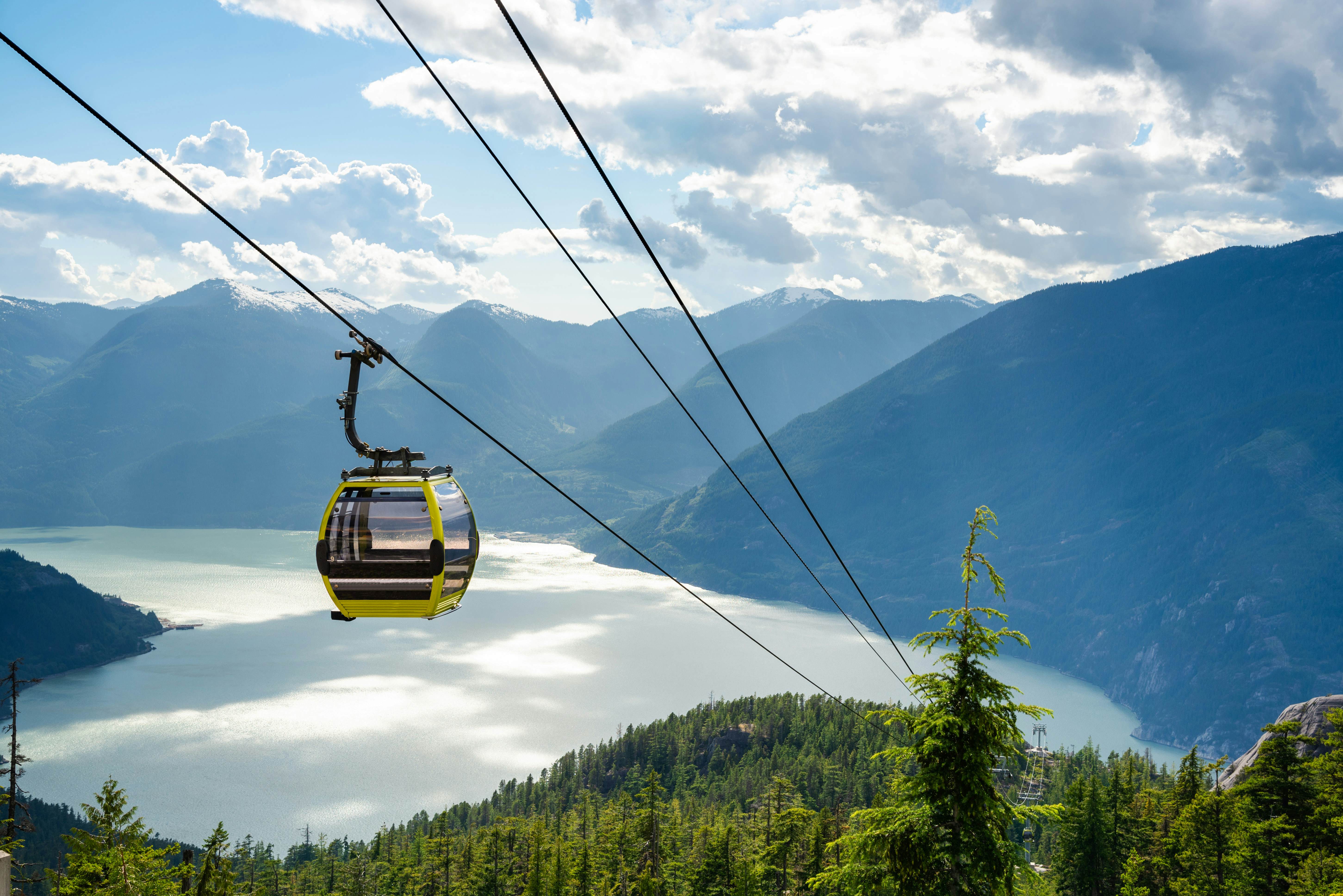 A cable car descends in front of beautiful mountain scenery.