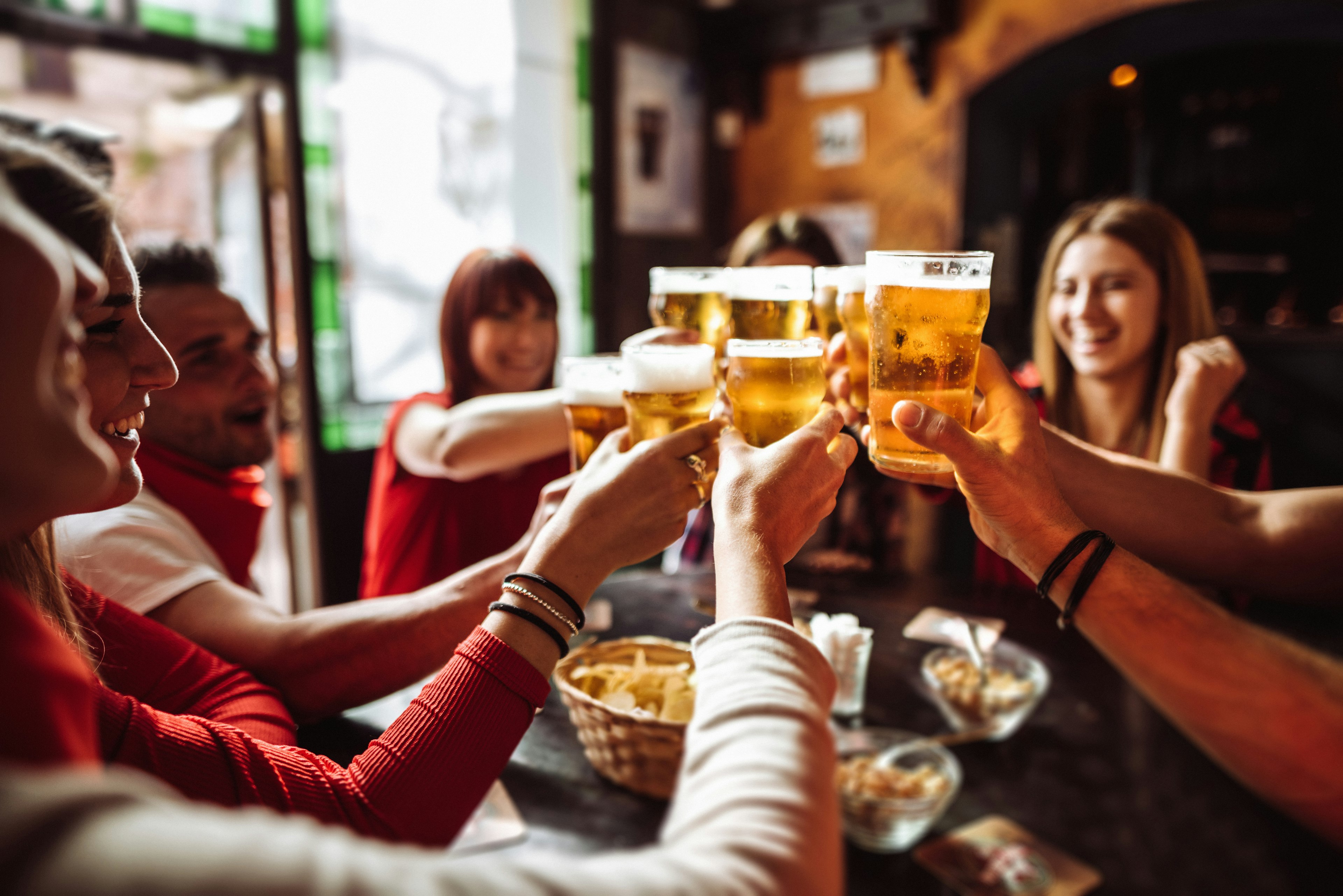 Group of people toasting beers at a pub