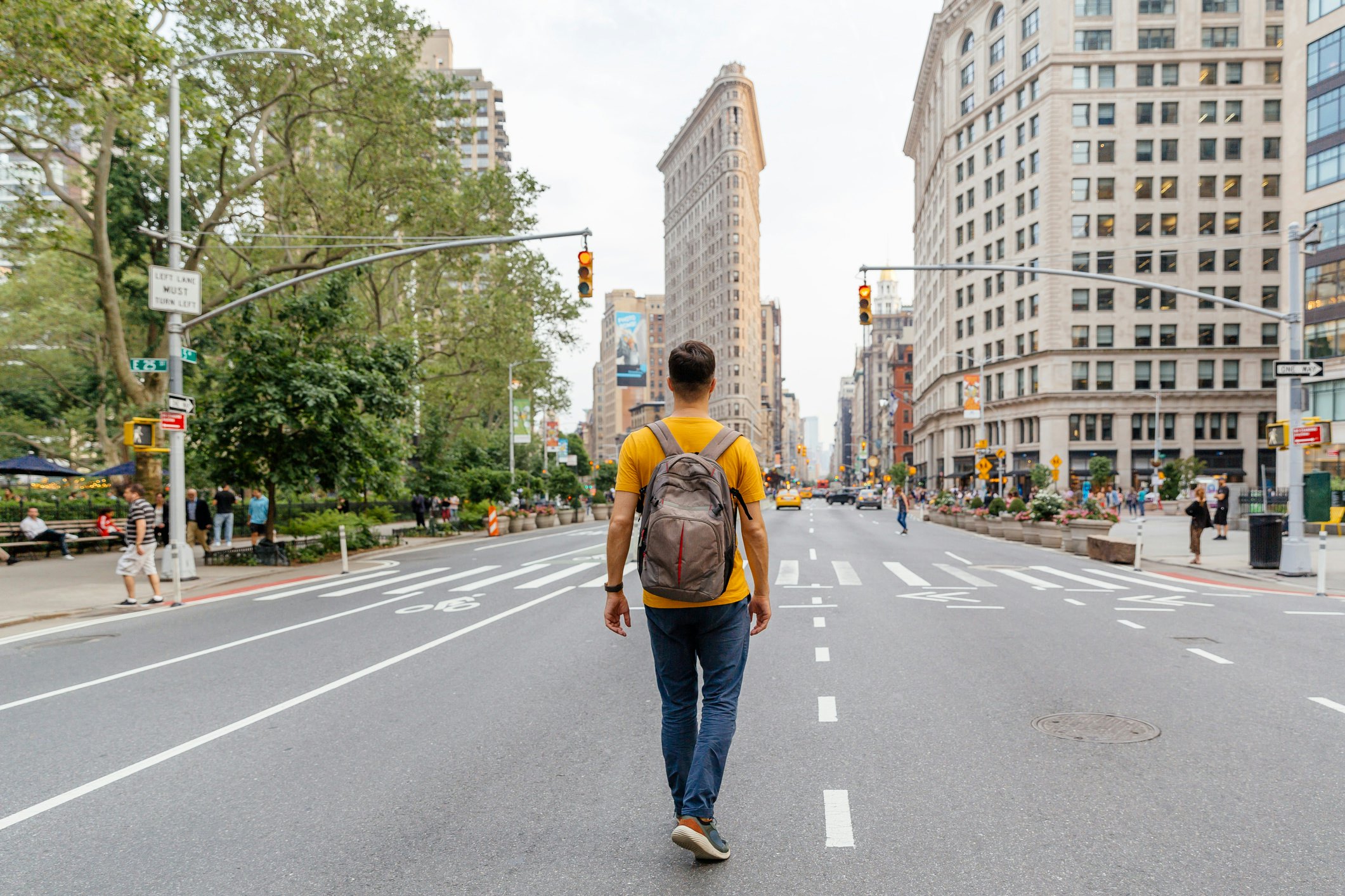 Young man walking on Fifth Avenue towards Flatiron Building, rear view