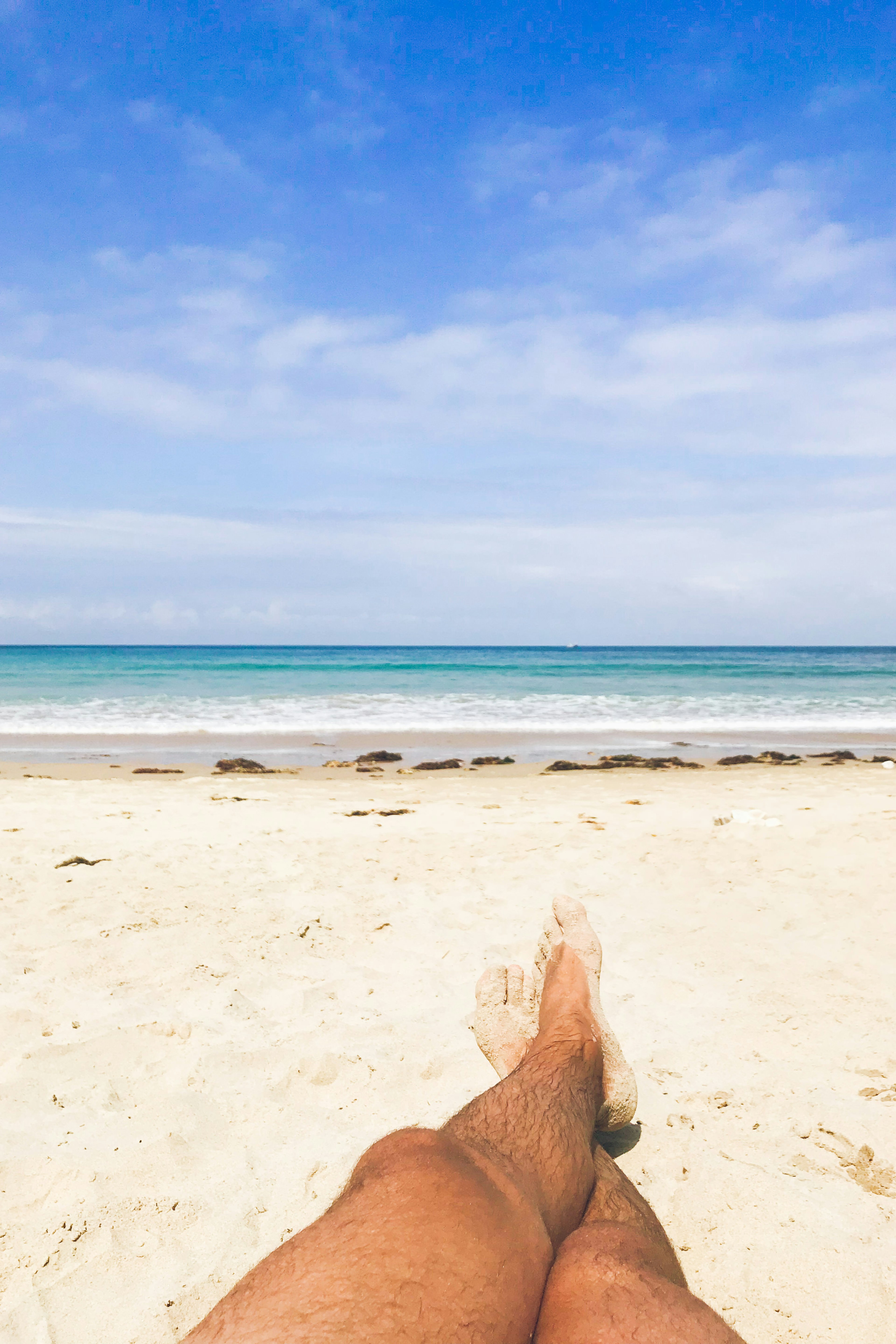 Man’s feet relaxing on the nudist beach of Torimbia, council of Llanes, north of Spain.