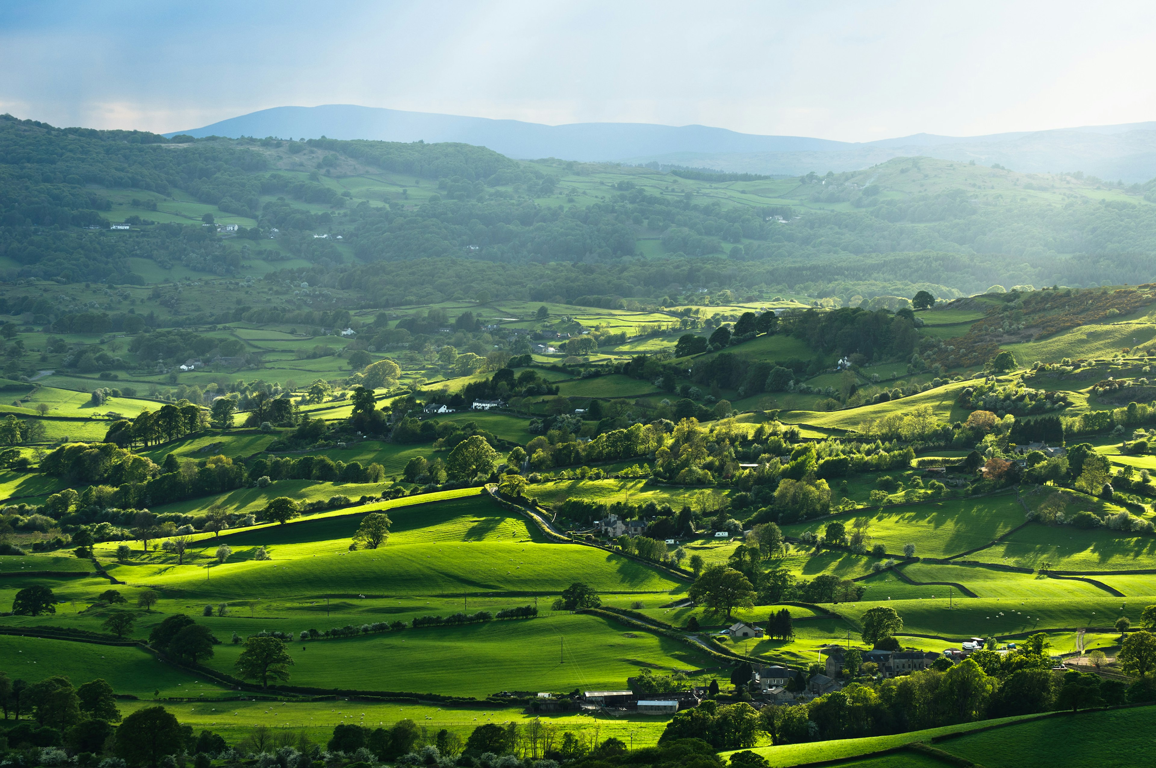 Rays of sunlight illuminating meadows, woods and villages in the Lyth Valley, Lake District, England