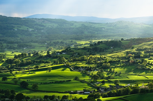 Rays of sunlight illuminating meadows, woods and villages in the Lyth Valley, Lake District, England