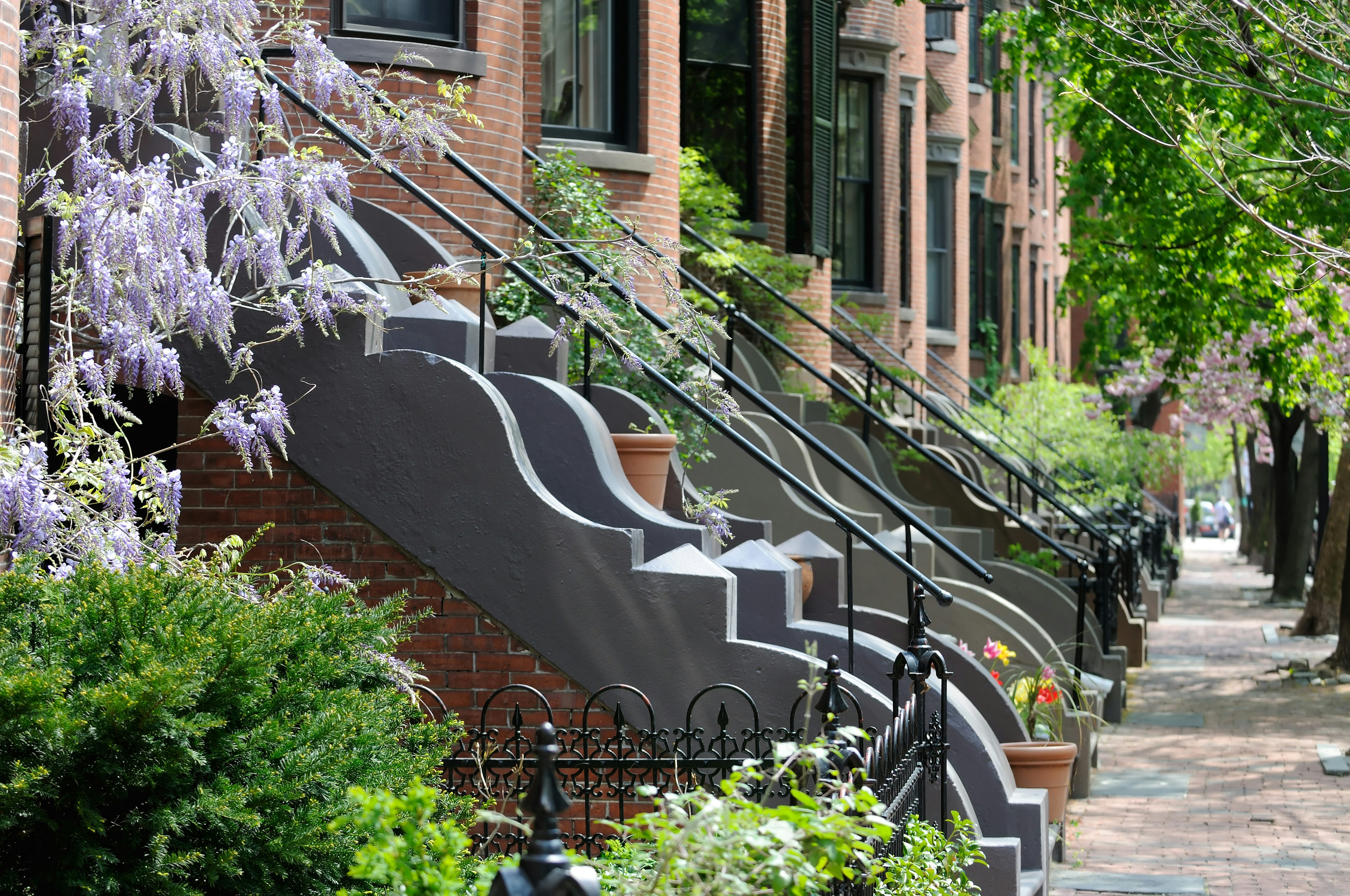 A sidewalk with steps up to Victorian buildings