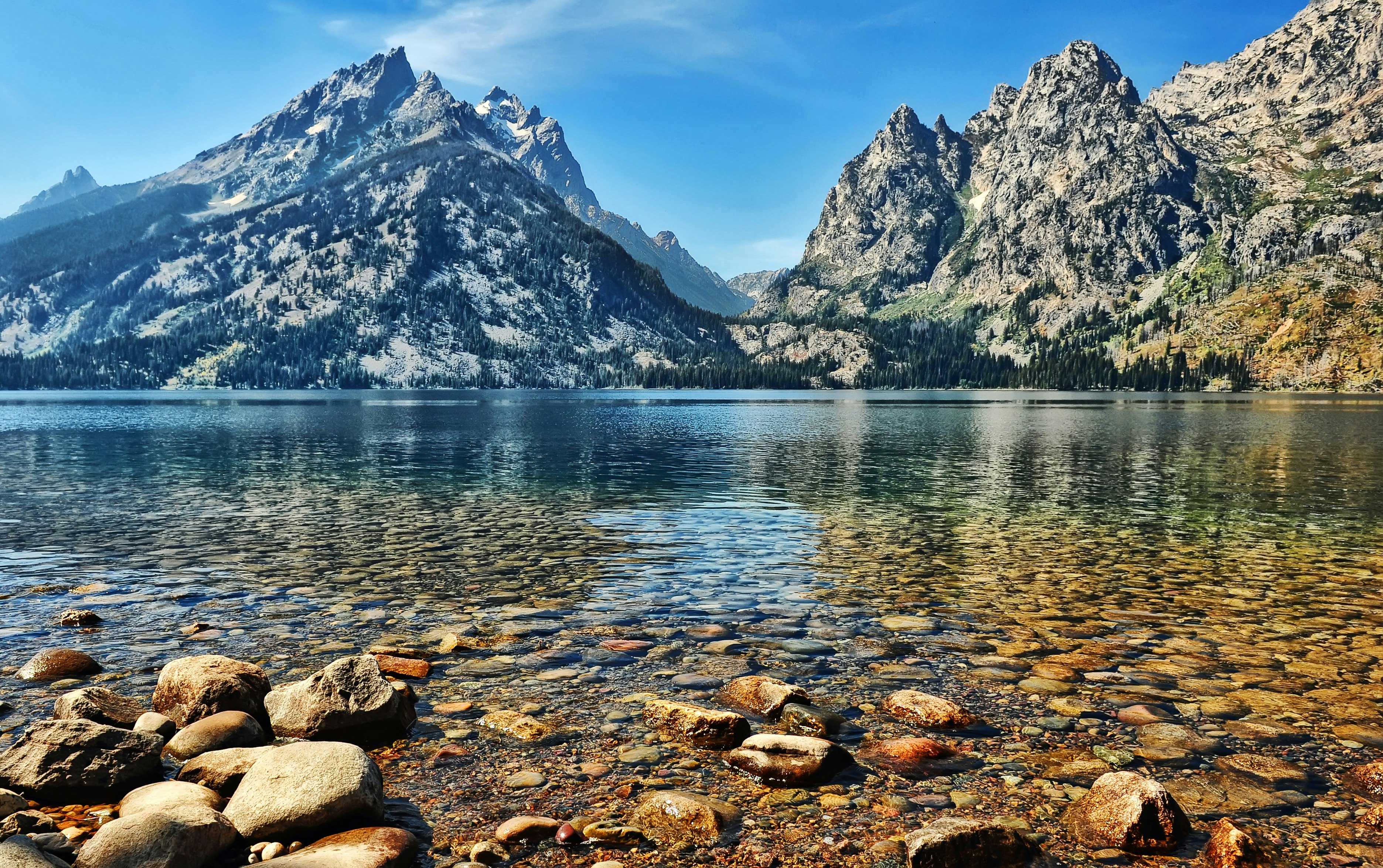 The clear water and stony bottom of Jenny Lake agains the backdrop of the Grand Teton peaks