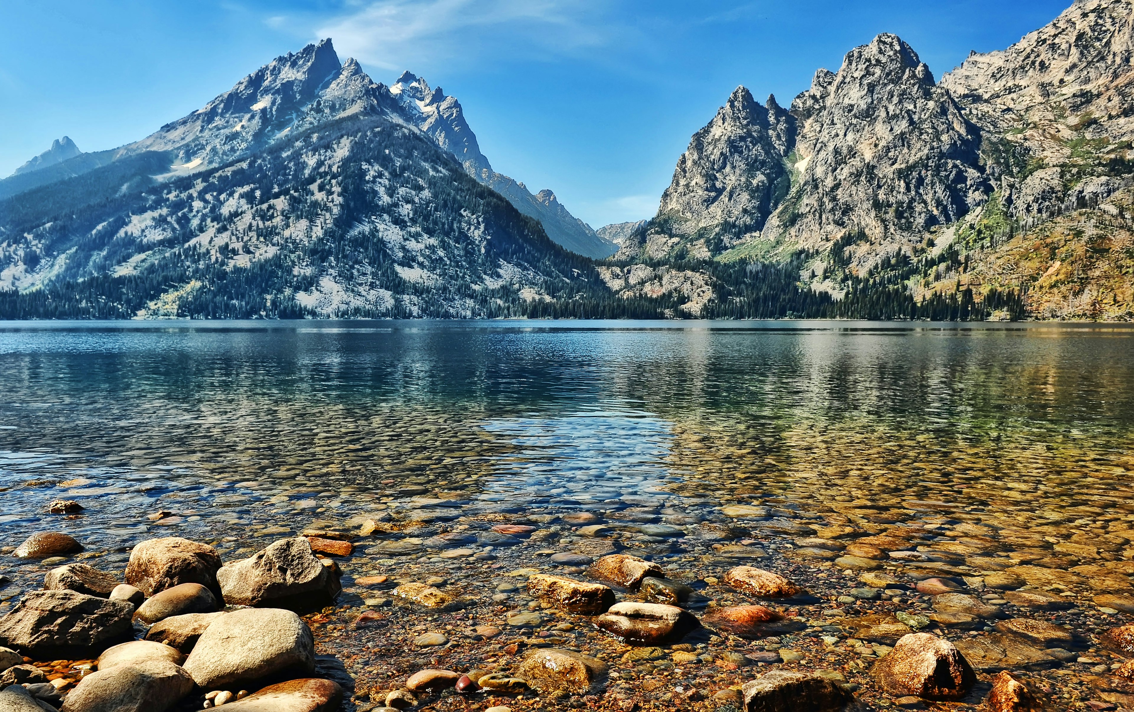 The clear water and stony bottom of Jenny Lake agains the backdrop of the Grand Teton peaks