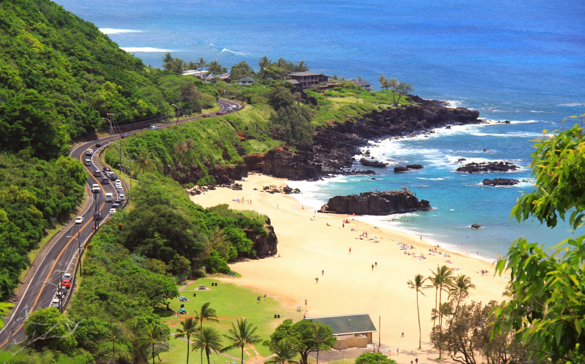 A road winds between a hillside and a beach.