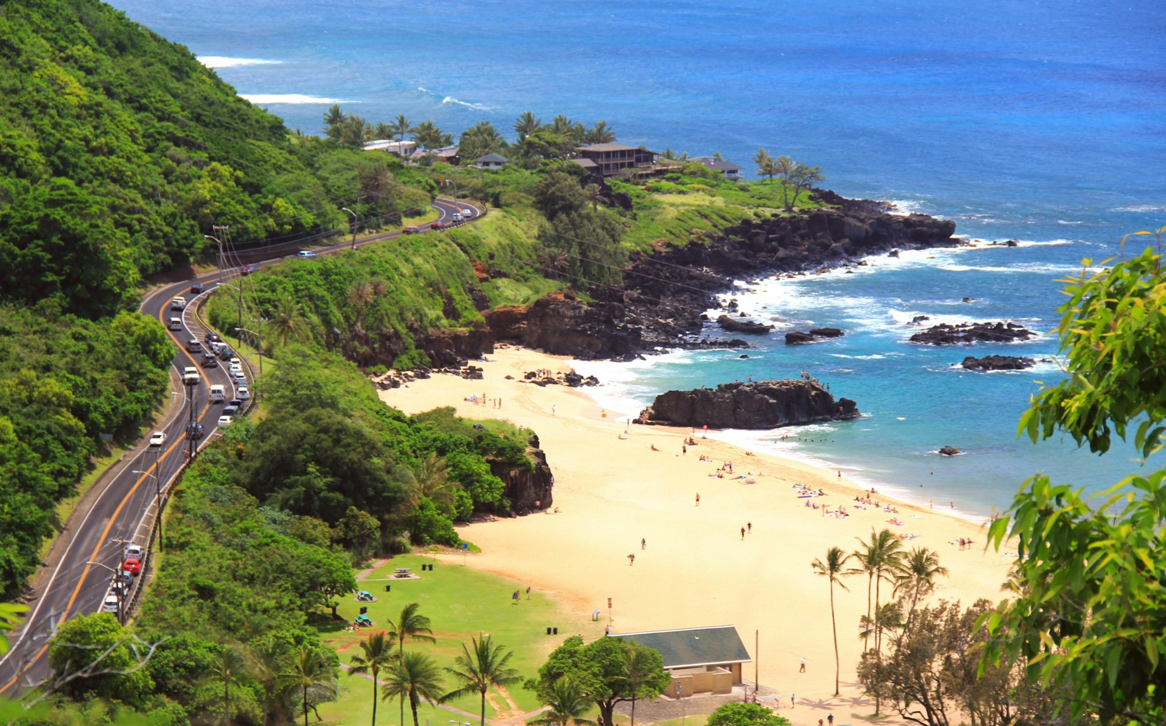 A road winds between a hillside and a beach.