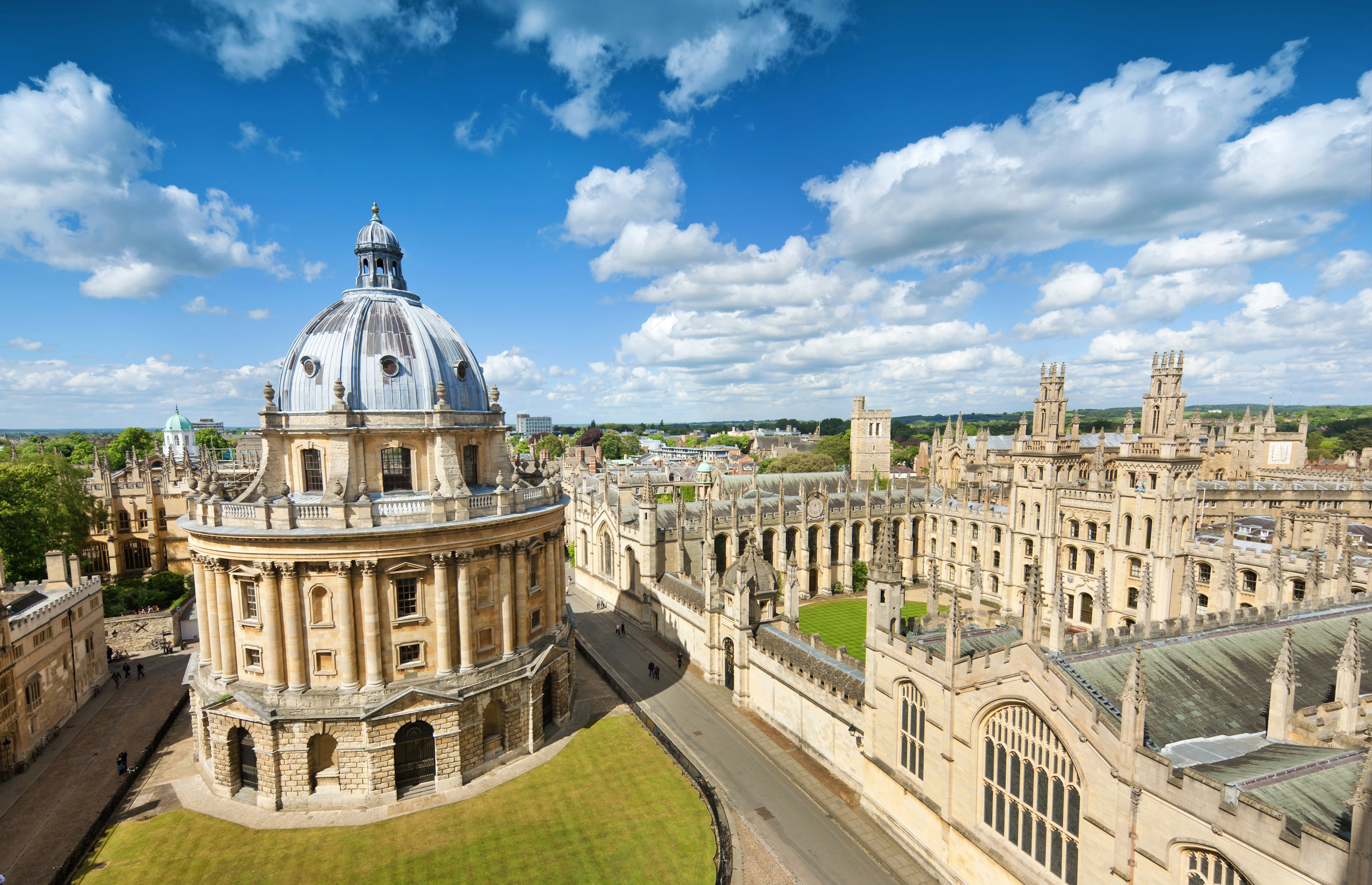 The sandstone-colored buildings of Oxford, including a round building in the middle of a green, and spires on surrounding buildings