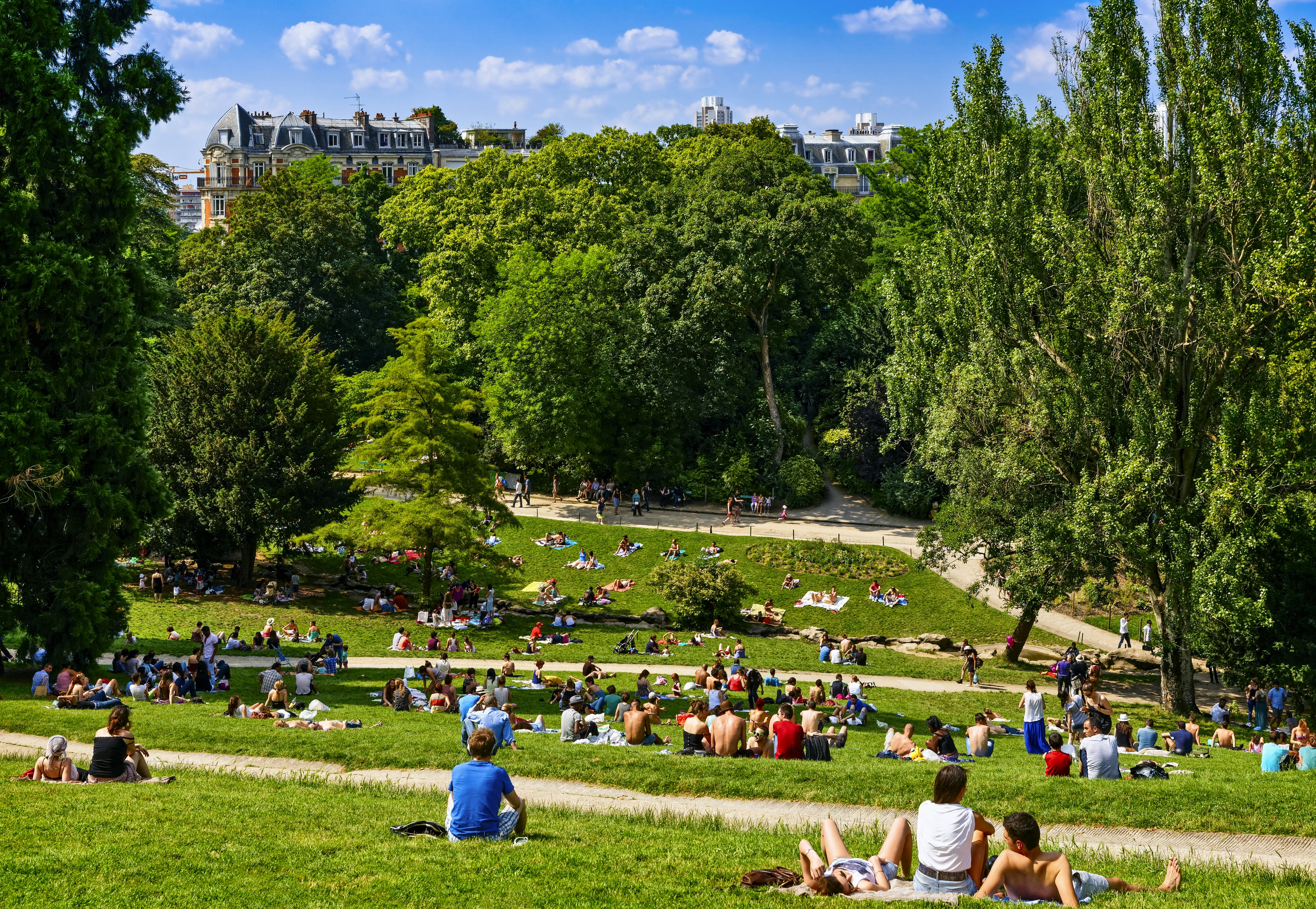 People sit on lush green grass in a Paris park.