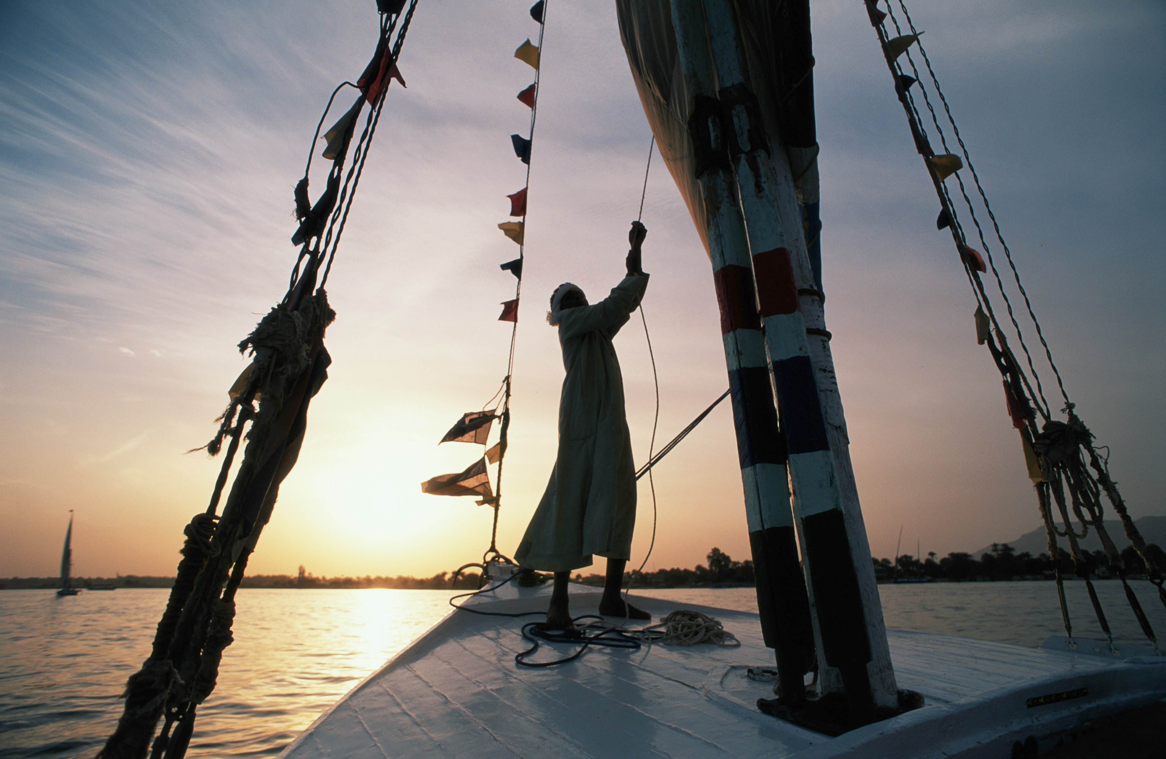 A man sails a felucca on River Nile at sunset Aswan, Egypt