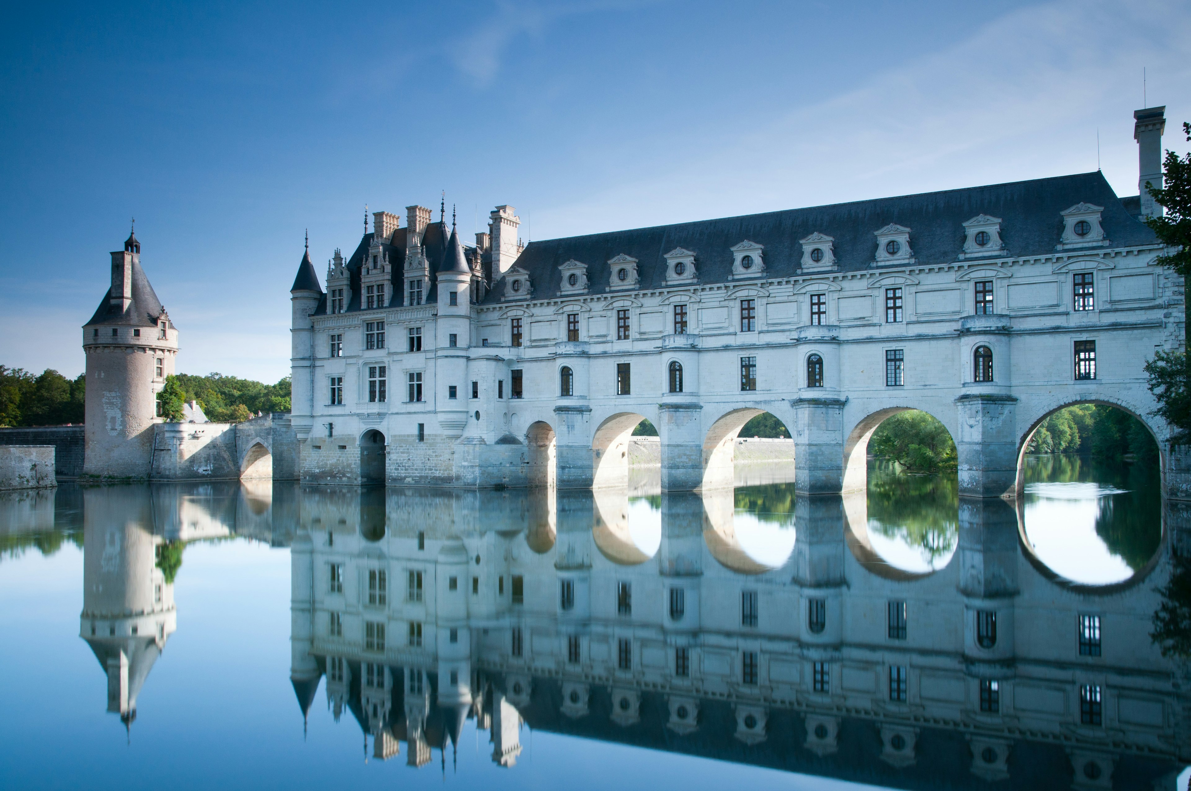 A large white chateau built over a river, with four large archways for the water to pass under