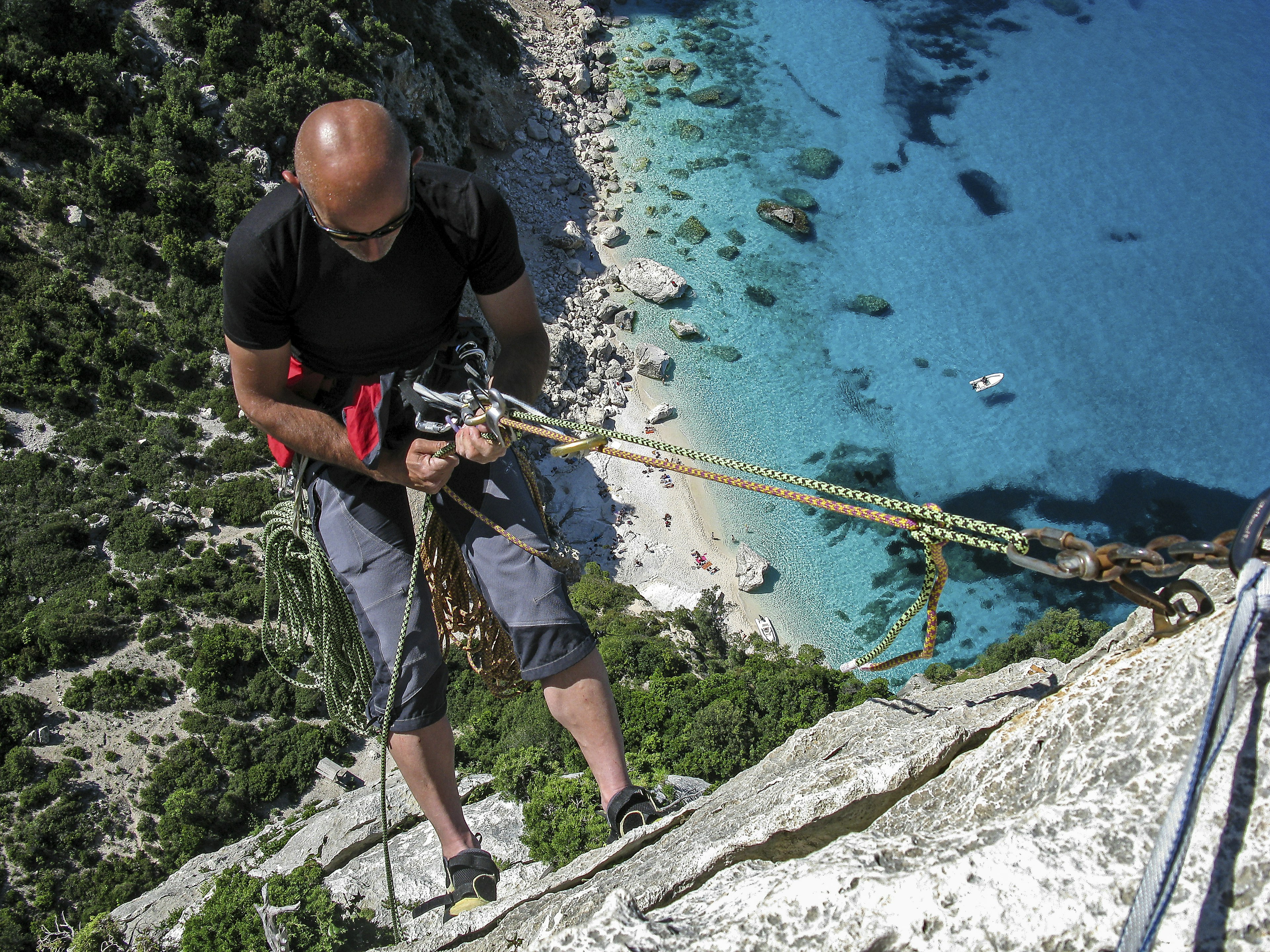 A man abseils down a cliff to Cala Goloritzè from Aguglia in Sardinia.