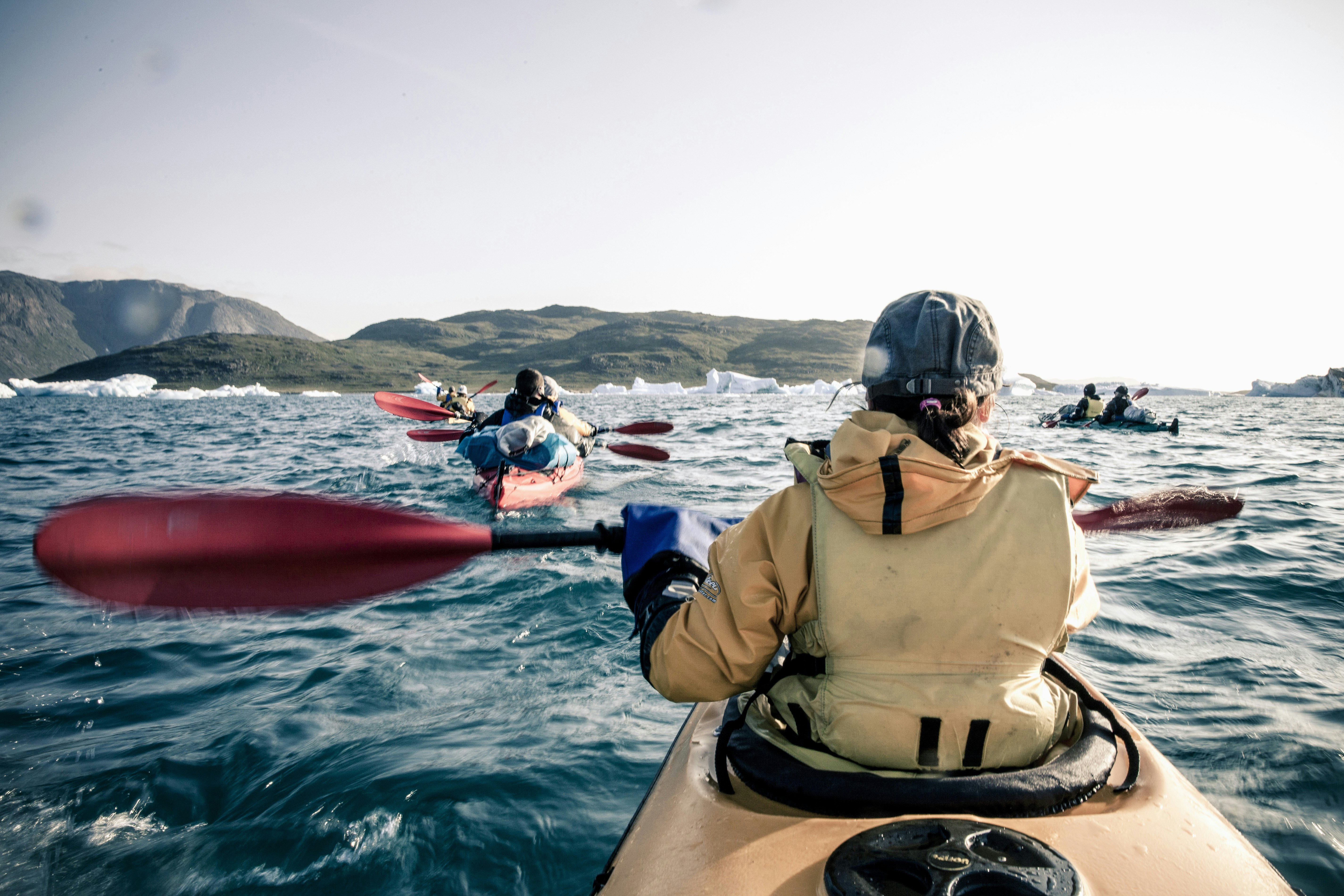 Women paddle in kayaks in the waters of Greenland