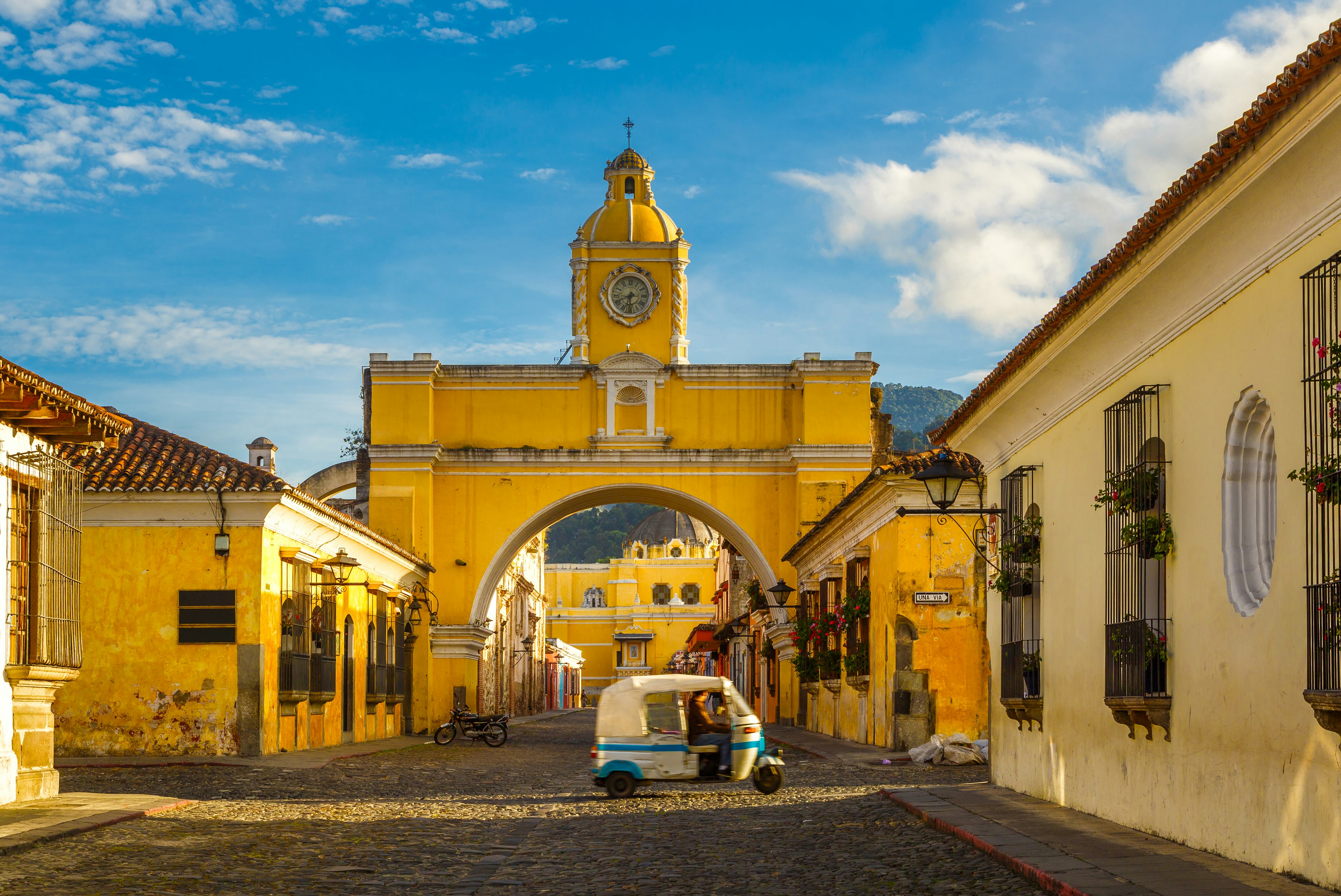 A tuk-tuk taxi passes the Arch of Santa Catalina in Antigua, Guatemala.