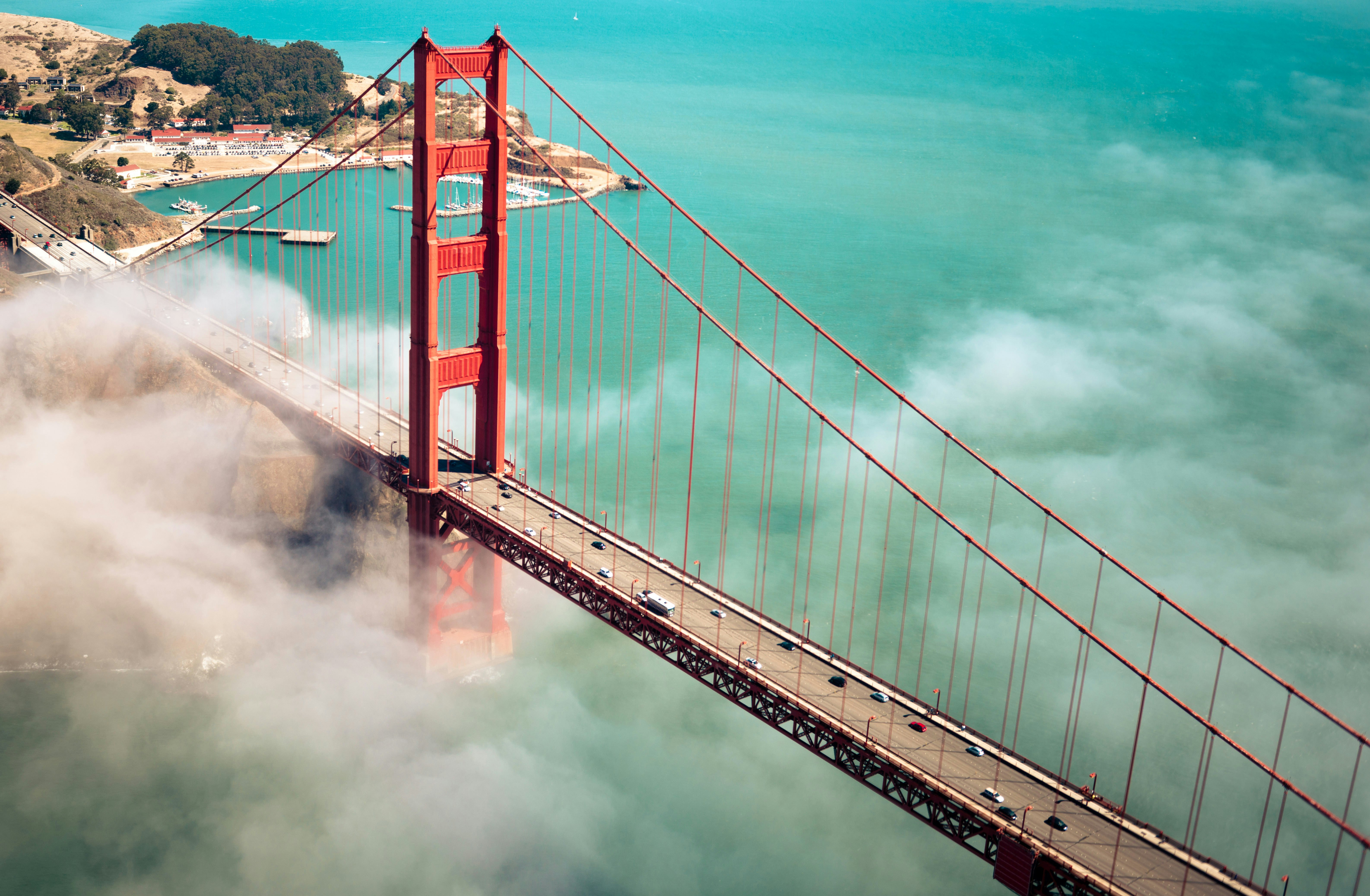 Aerial view of San Francisco Golden Gate Bridge, partially covered in mist with the shore in the distance