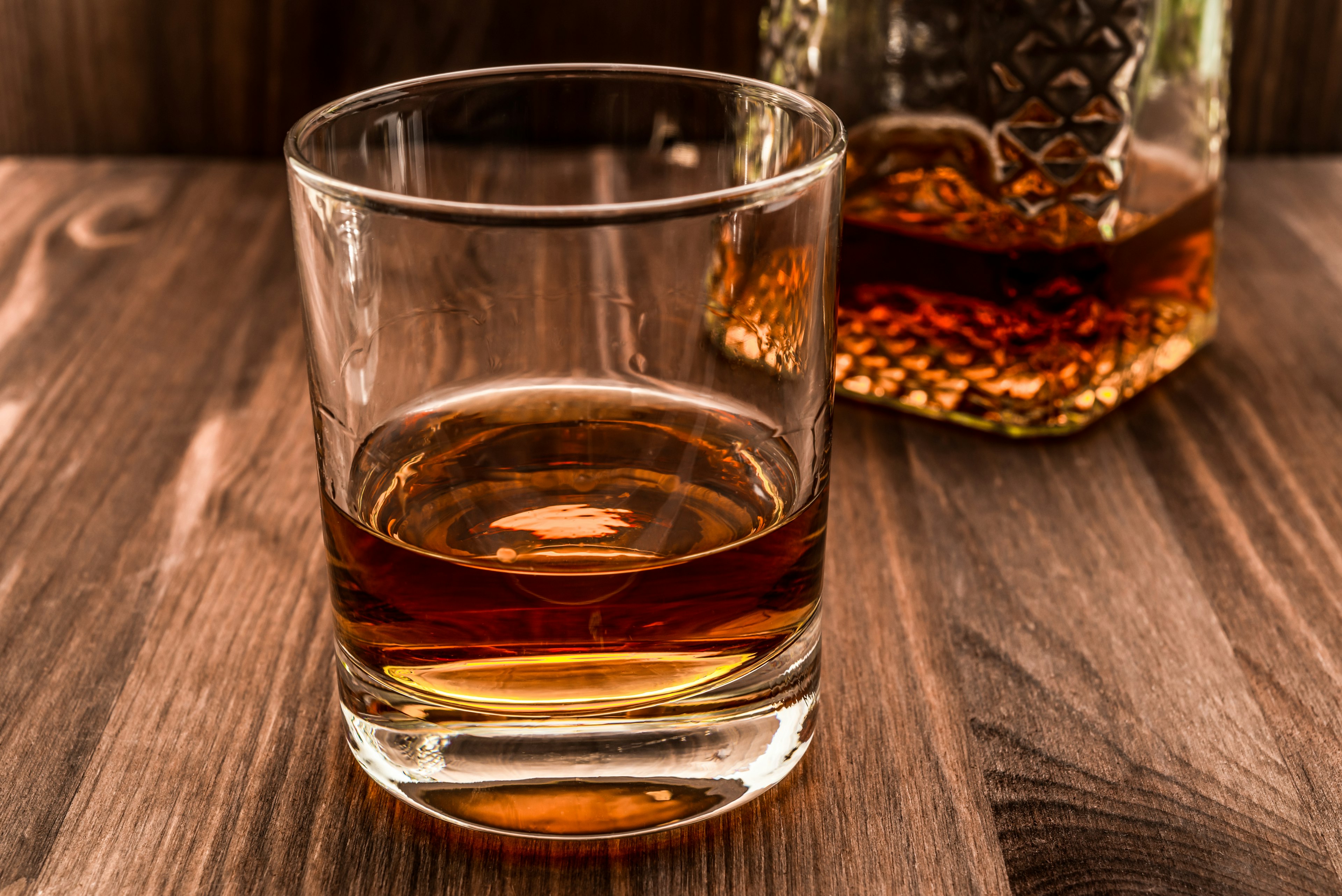 Decanter of whiskey and a glass on a wooden table.