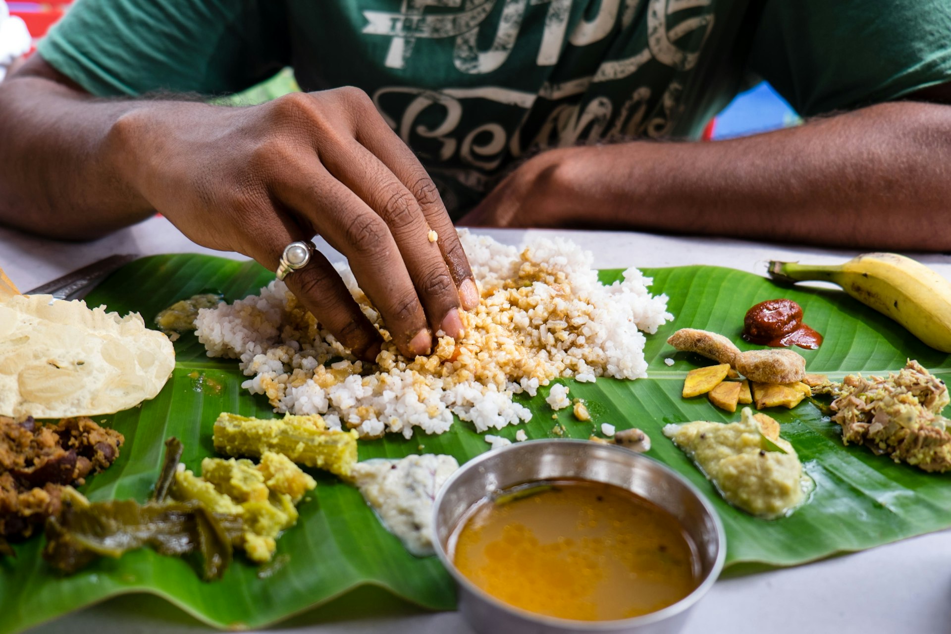 A man eats a banana leaf thali (plate meal) with his fingers in India.